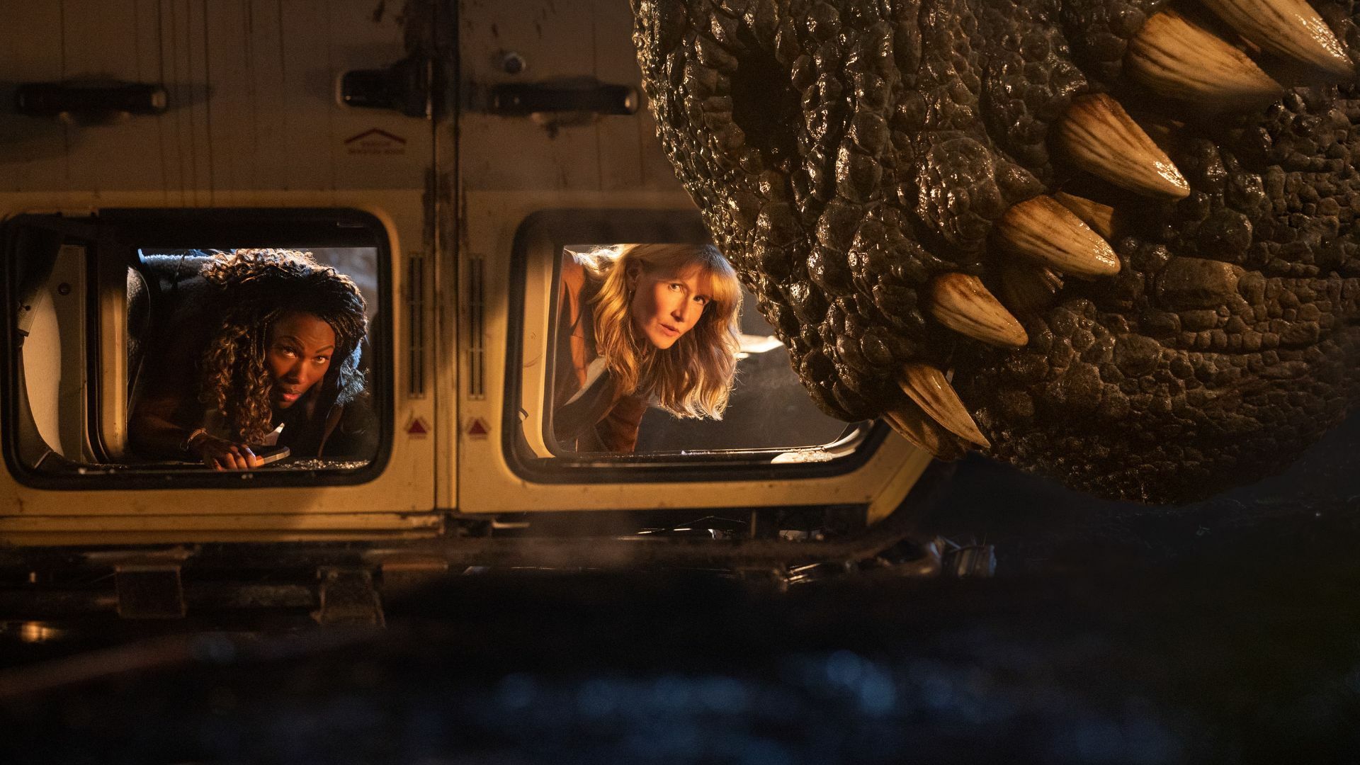 Two women trapped in a toppled truck by a T-Rex. 