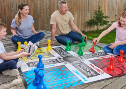 A family sits outside and plays a giant version of the board game Sorry!