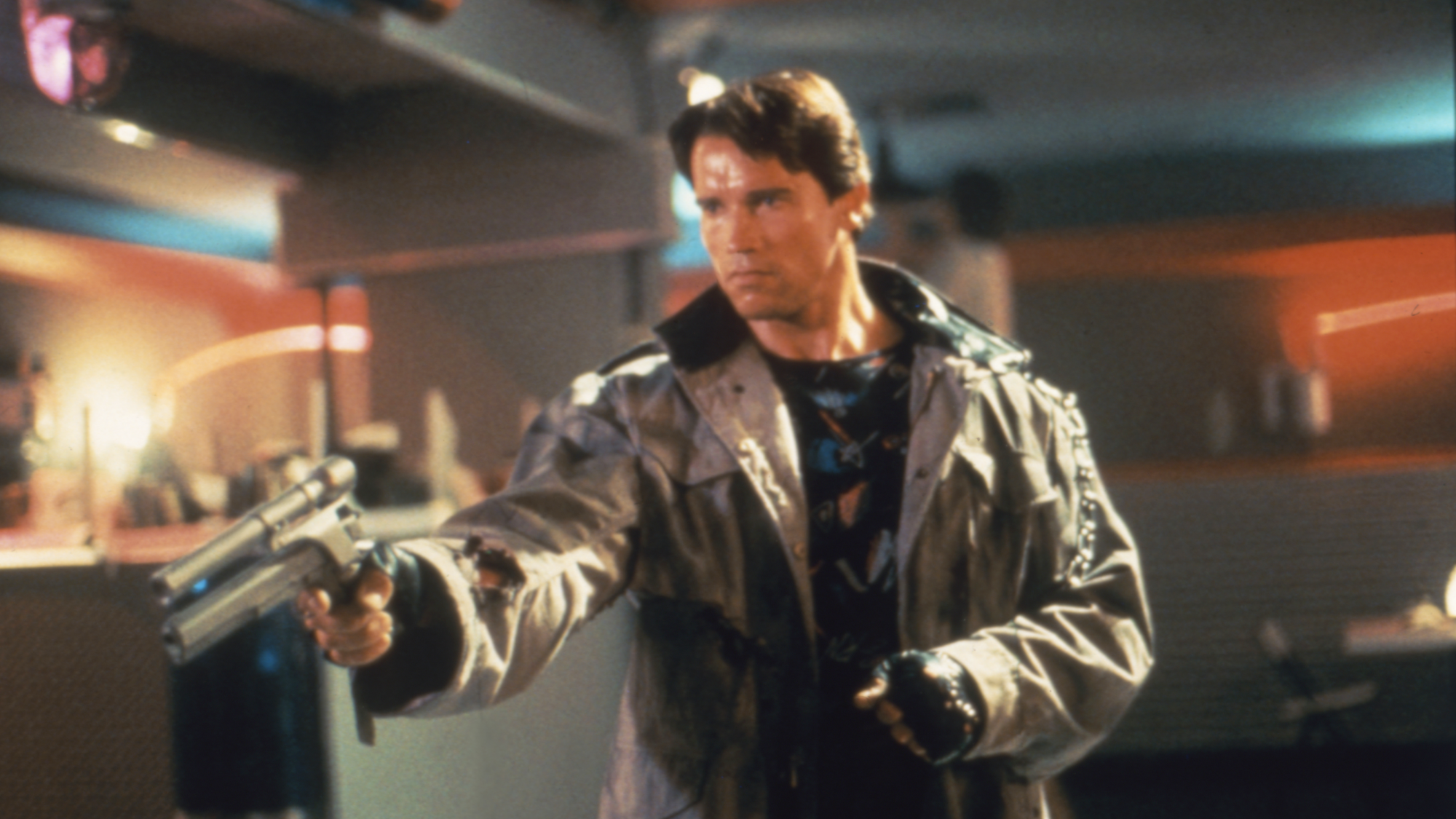 A man in a leather jacket points a gun.