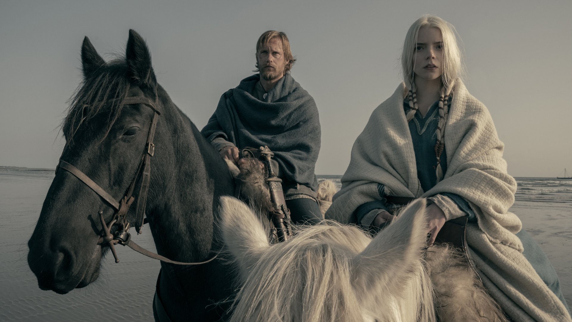 A man and woman sit on two horses in blankets,