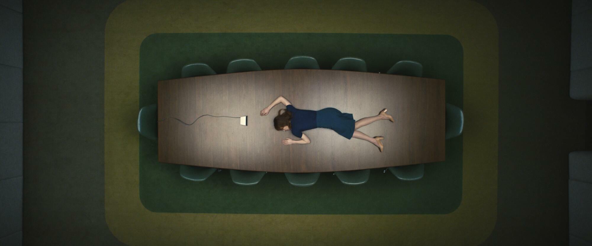 A woman lying on a conference room table.