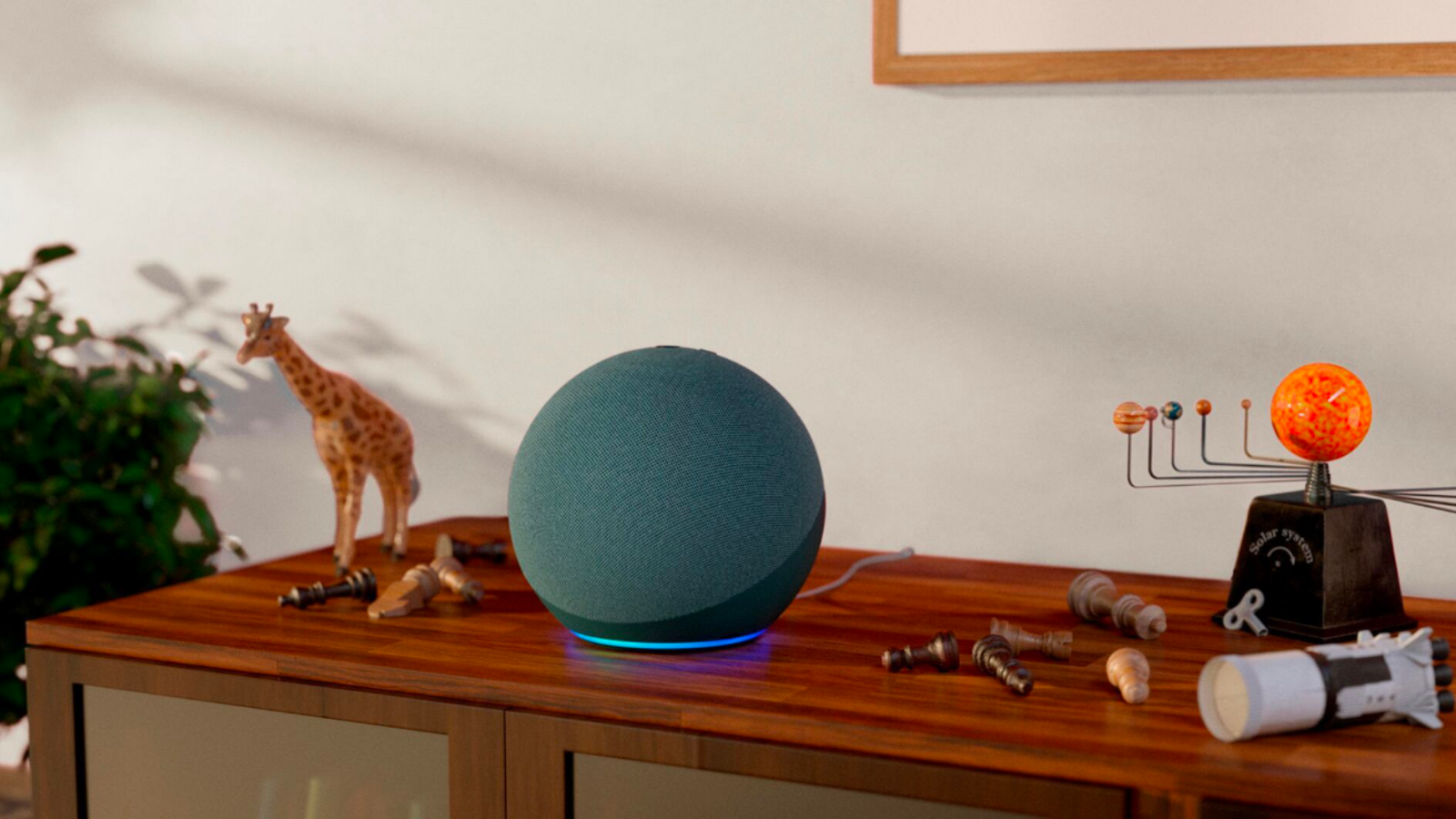 a twilight blue amazon echo on a wooden console next to a plastic giraffe toy and a model solar system