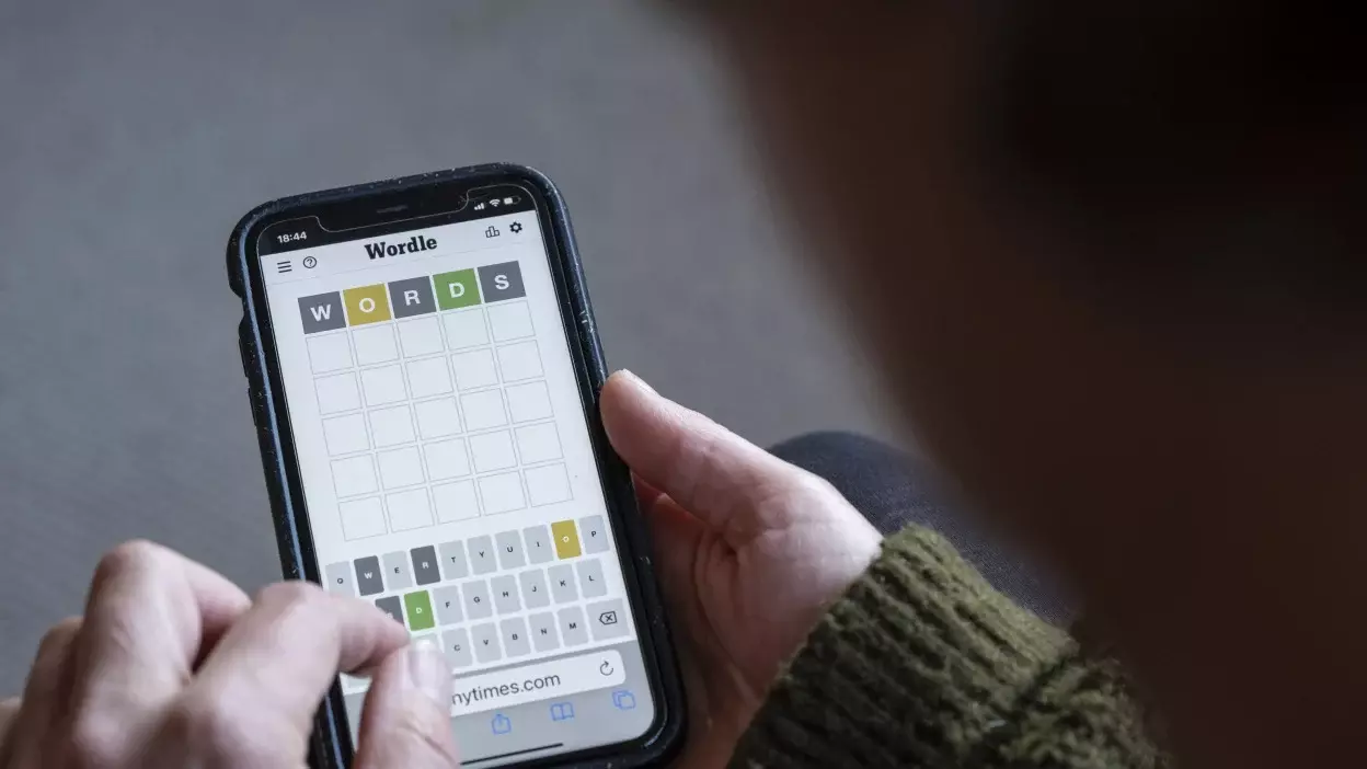 Woman plays Wordle on her smartphone from the living room of her home.