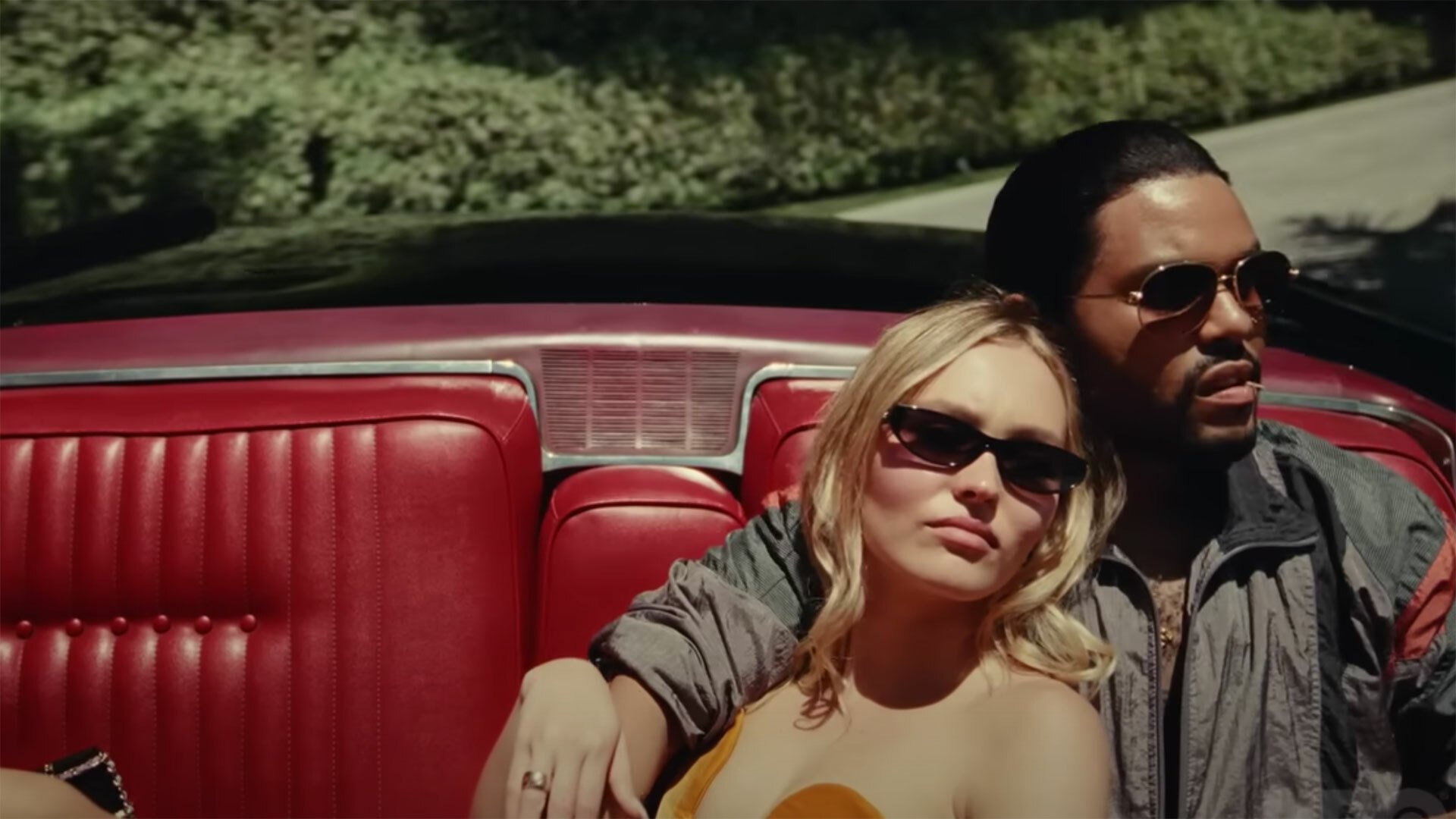 A man and a woman sit in a fast red car.