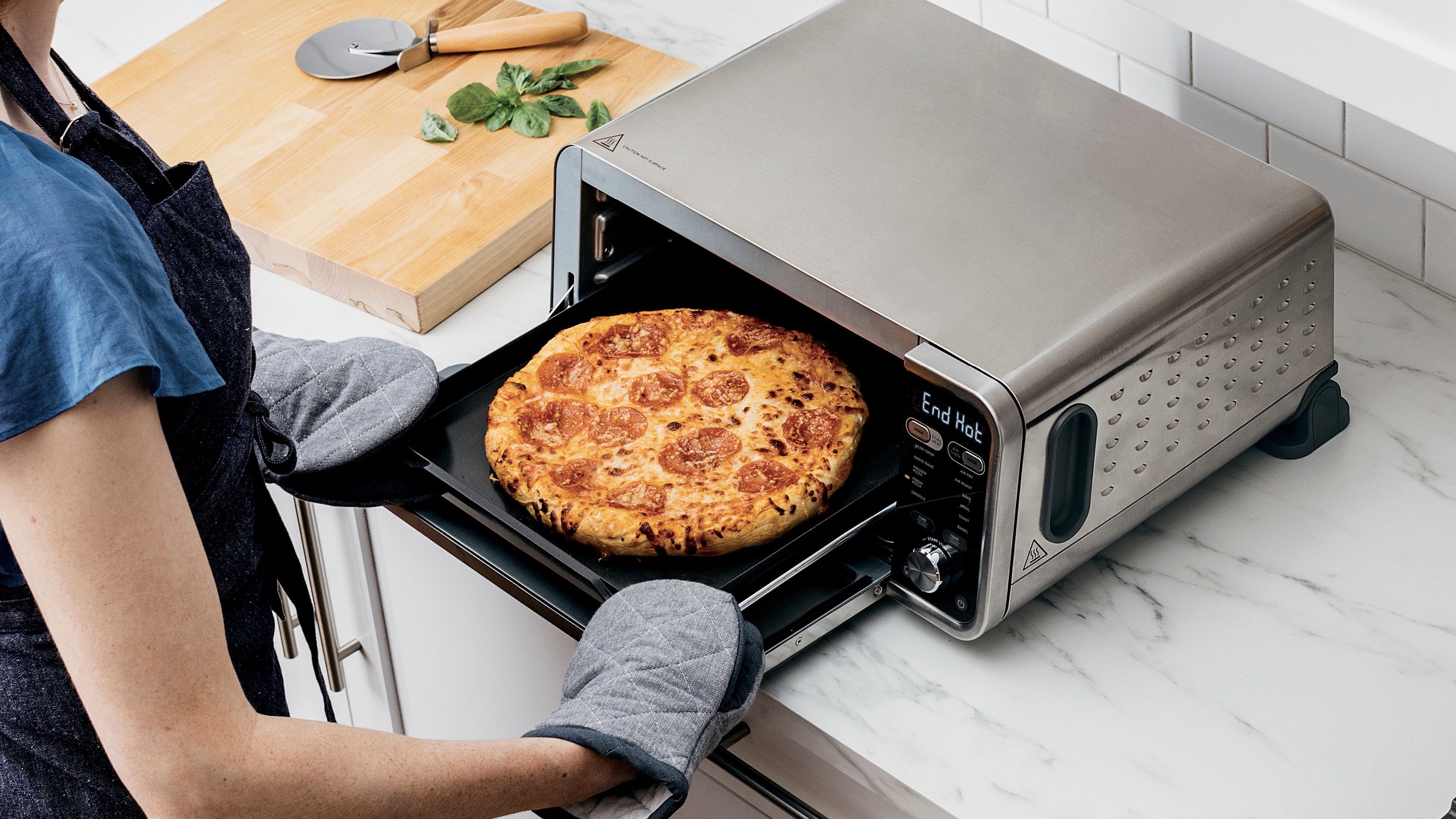 person pulling pizza out of ninja foodi oven