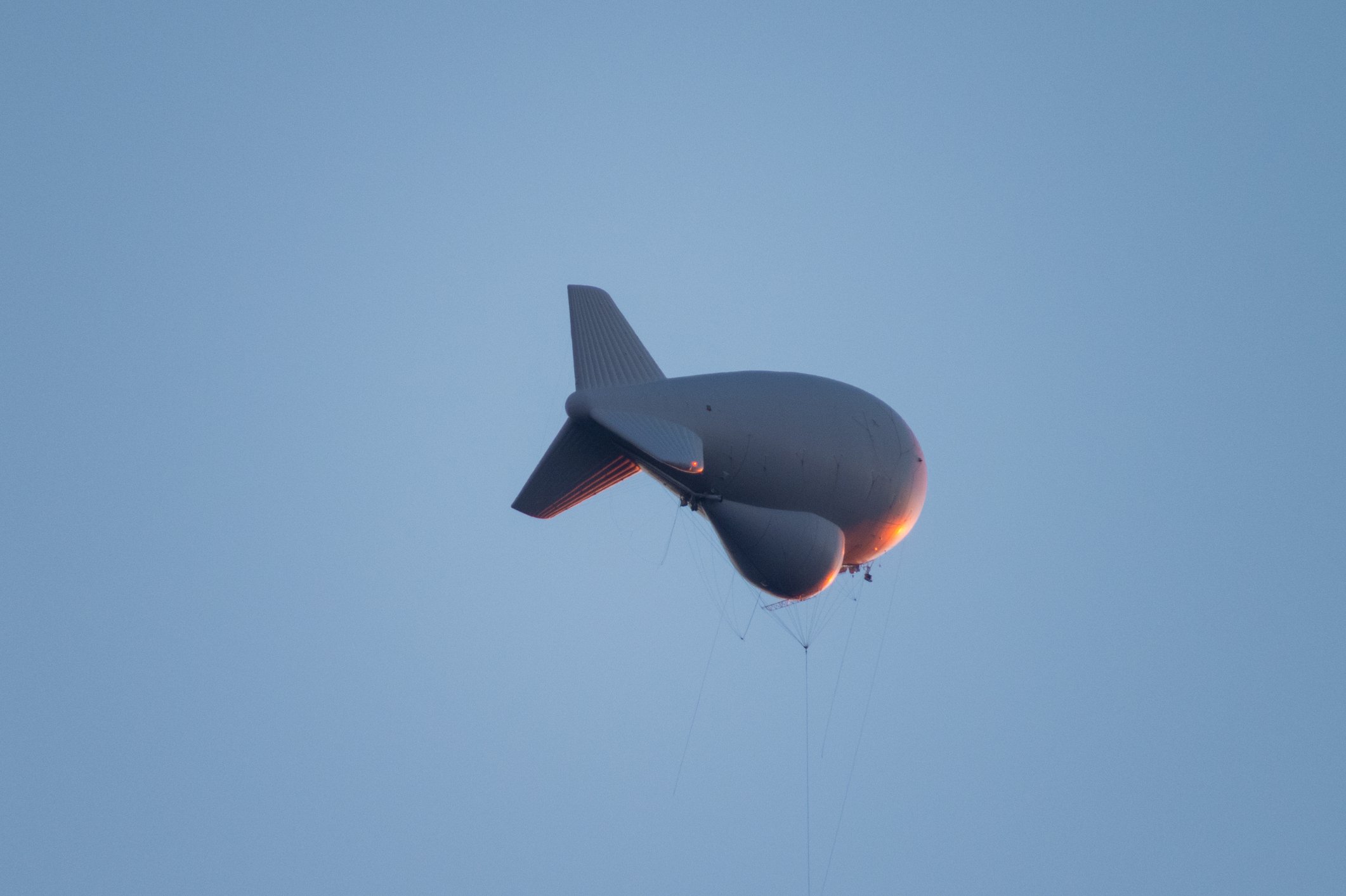 Aerostat is tethered high above the Huachuca Mountains with bright orange reflection from the setting sun.