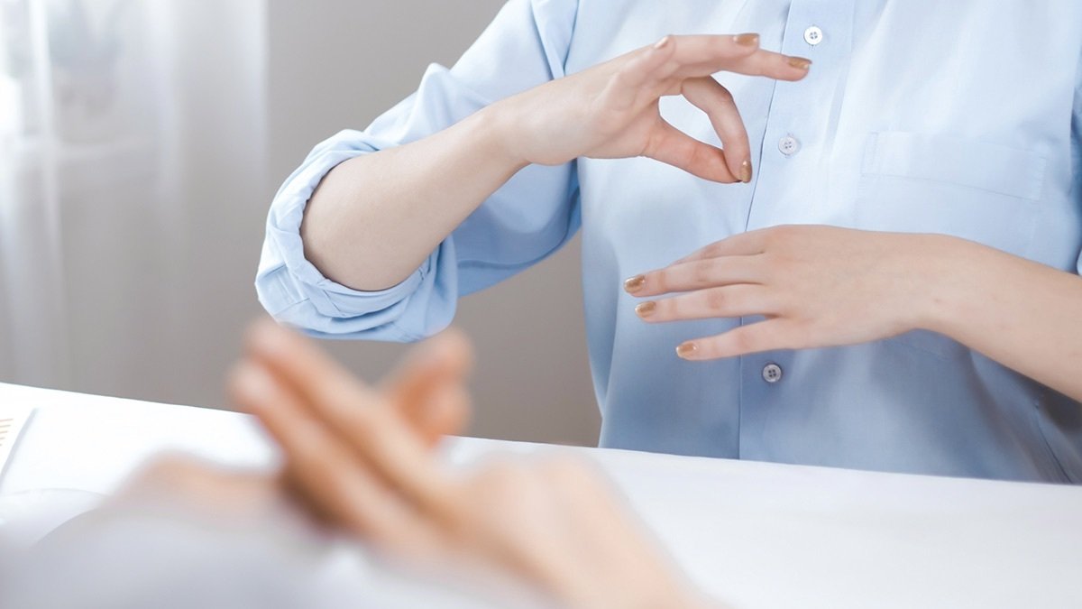 Person practicing ASL in a mirror.