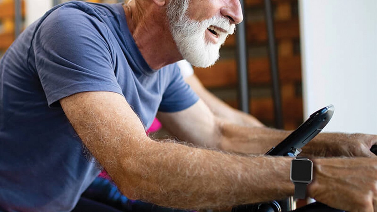 Smiling person on exercise machine wearing black smartwatch