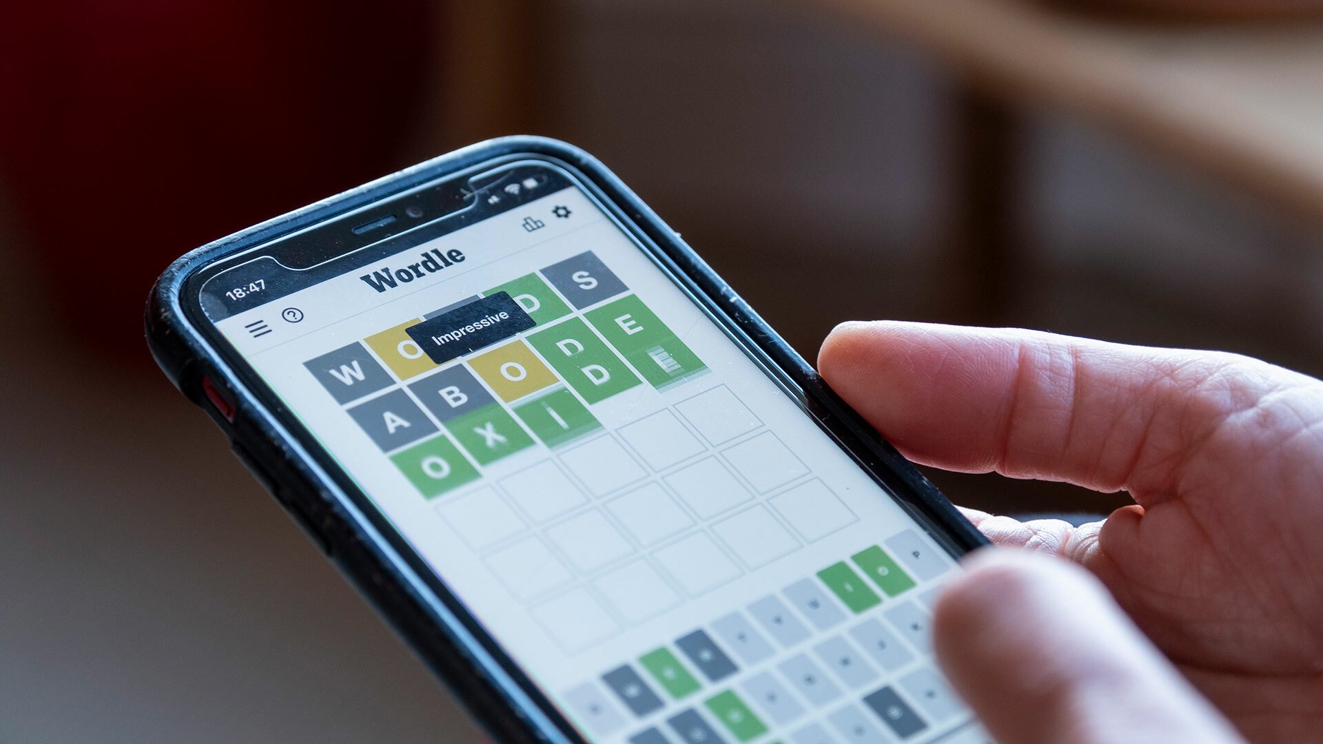 A person plays Wordle on a smartphone.