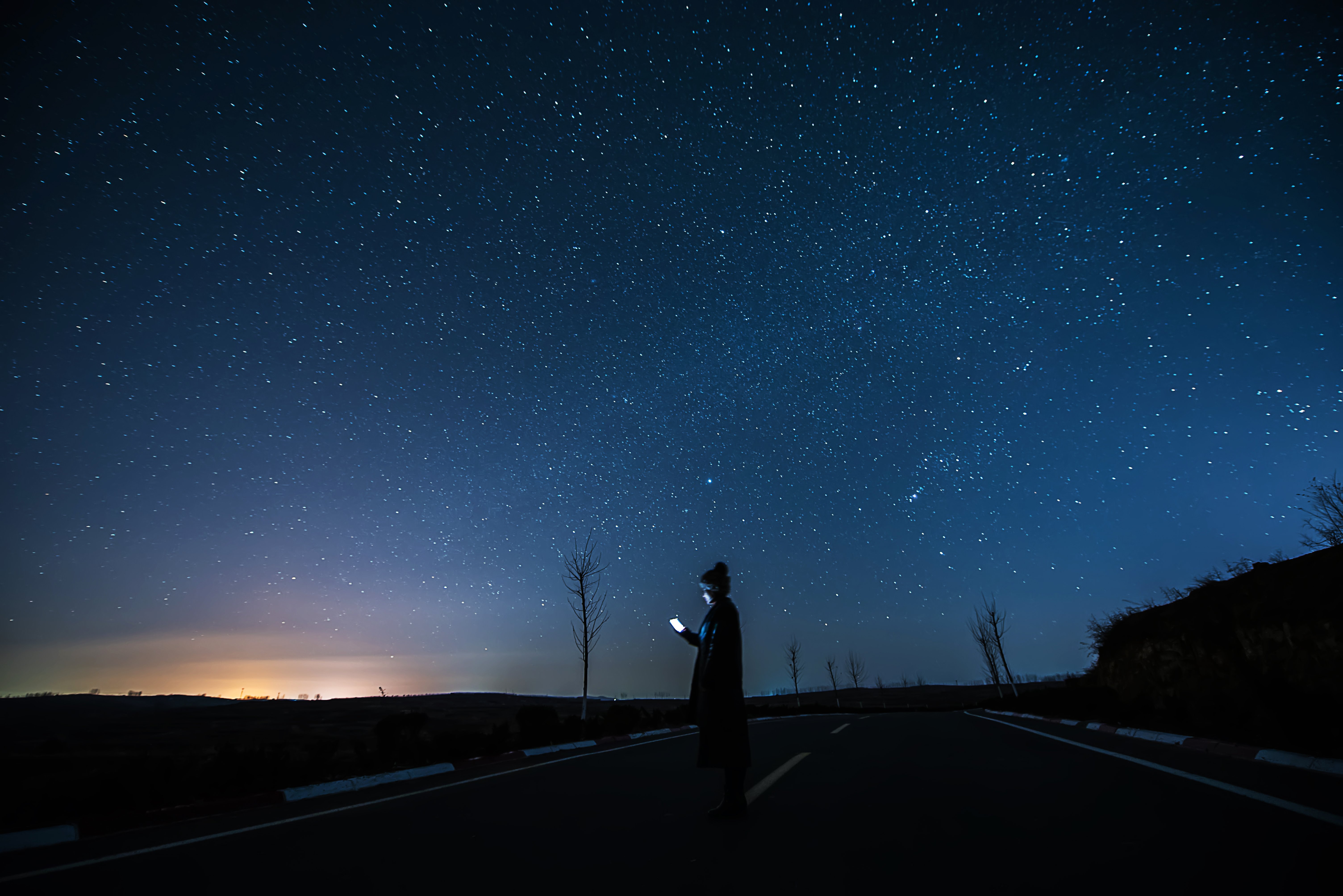Person using phone against a starry sky.