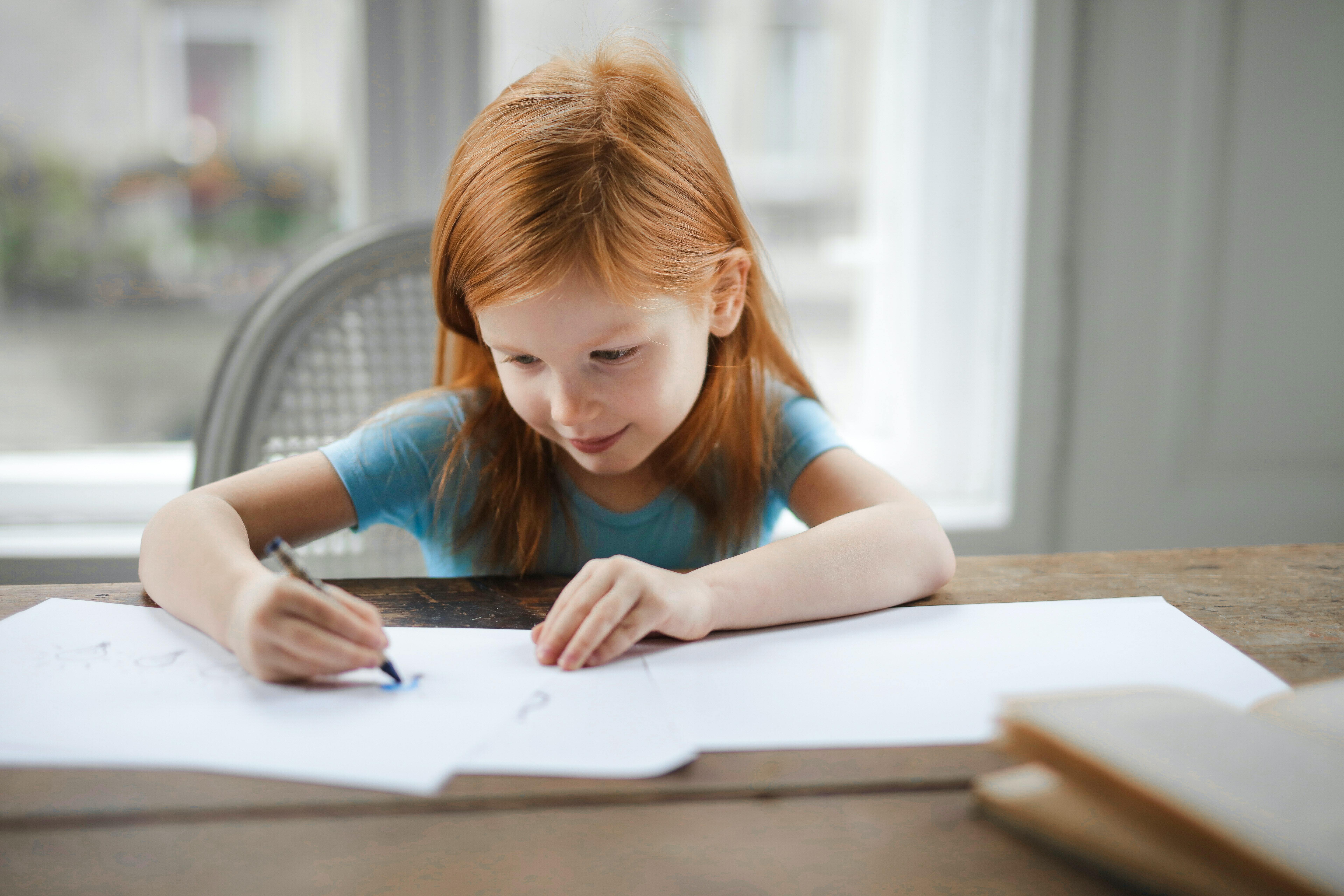 girl sitting at table in front of open notebooks