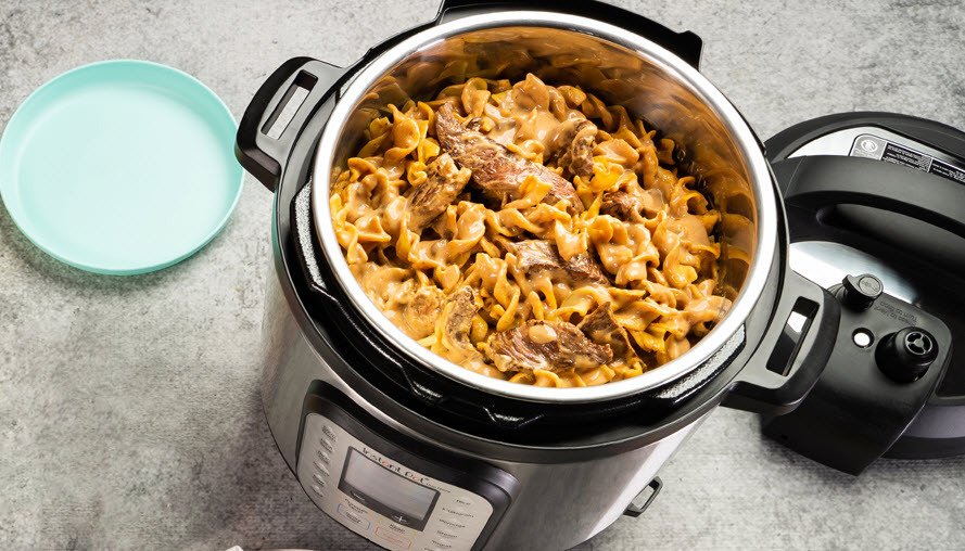 Instant Pot Duo Plus 9-in-1 9-quart multi-cooker containing noodles next to plate on a kitchen counter.