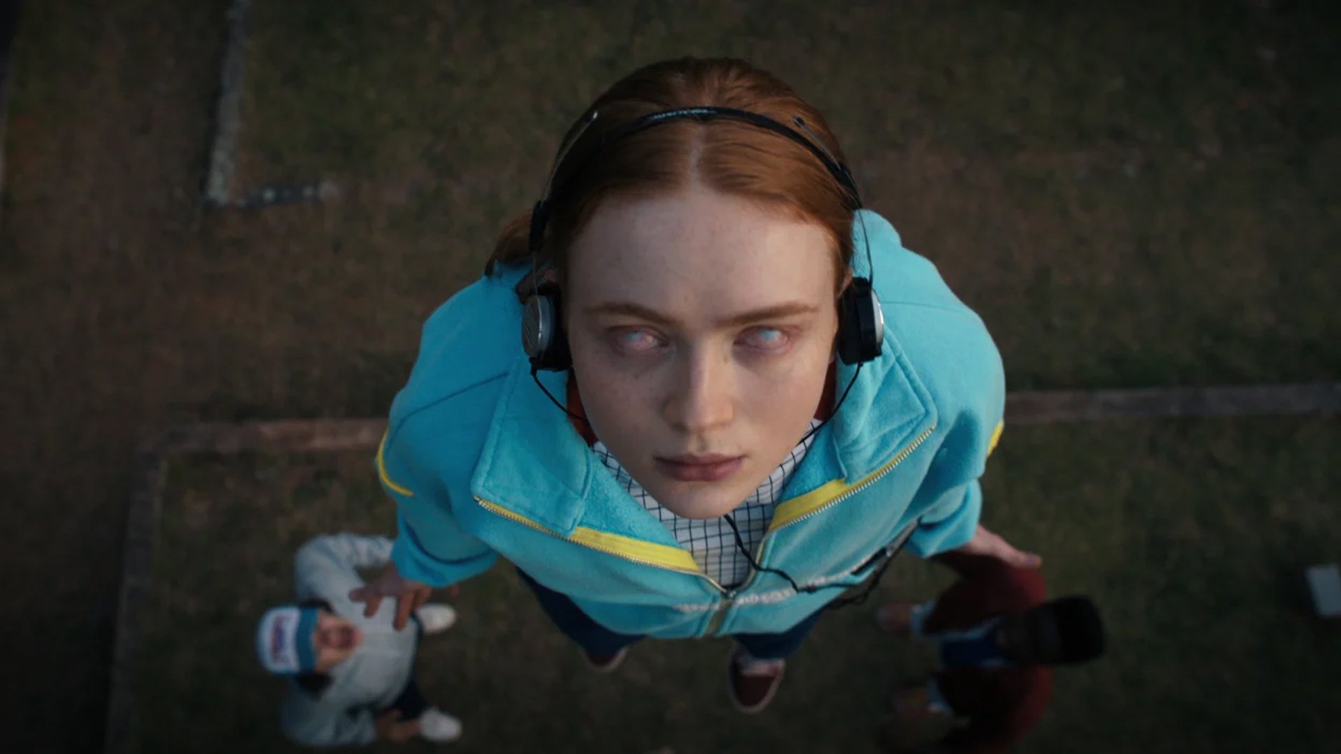 A girl looks up to the sky wearing headphones, with eyes gone misty.