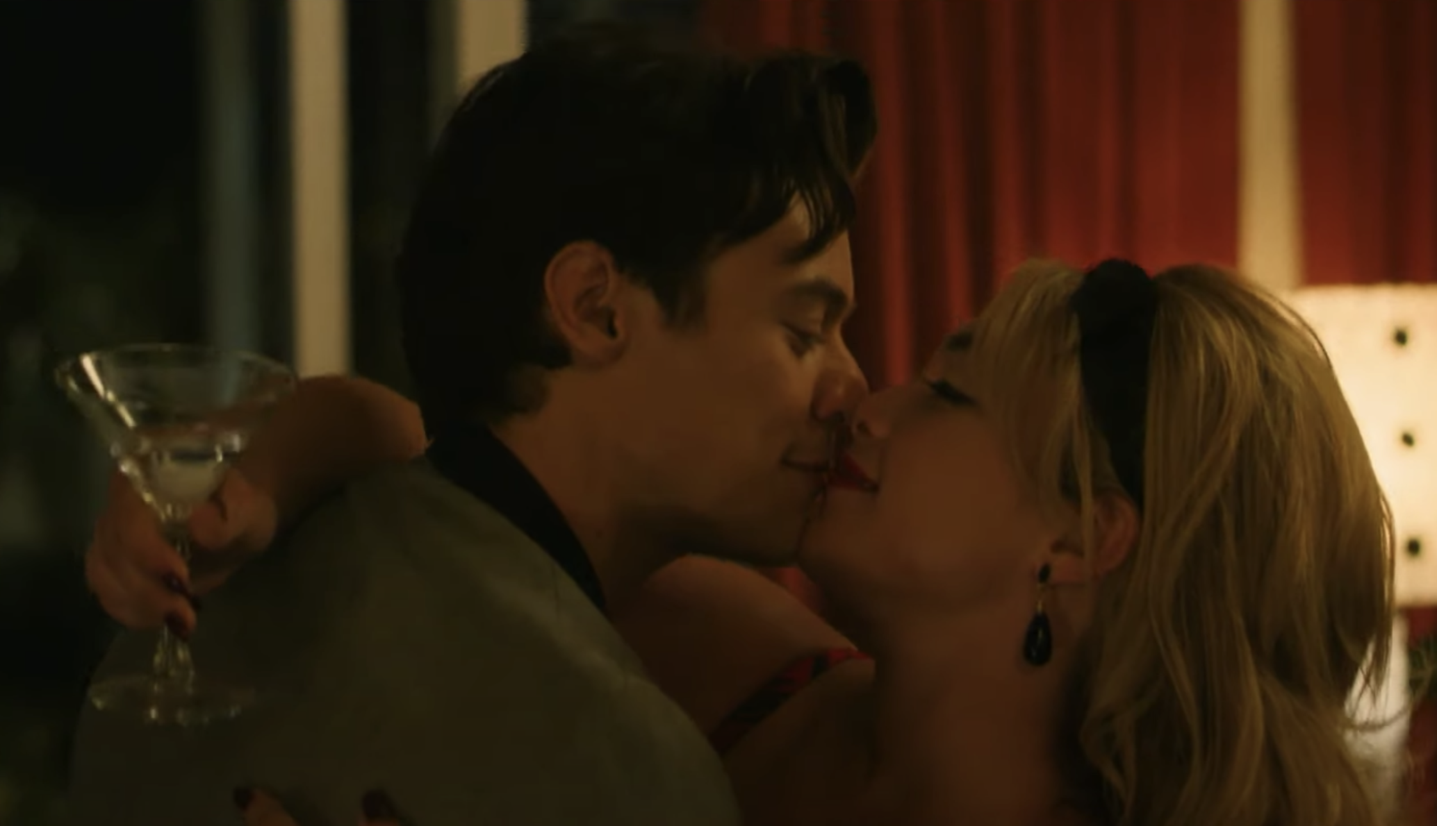 Harry Style and Florence Pugh kiss while she holds a martini glass