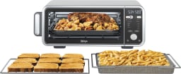 ninja foodi air fry oven filled with roast meat, with trays of toast and fries in front of it