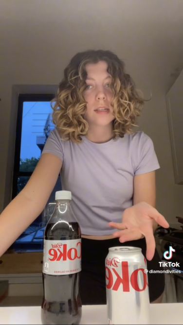 A screenshot of a TikTok of a woman pointing to a can of Diet Coke.