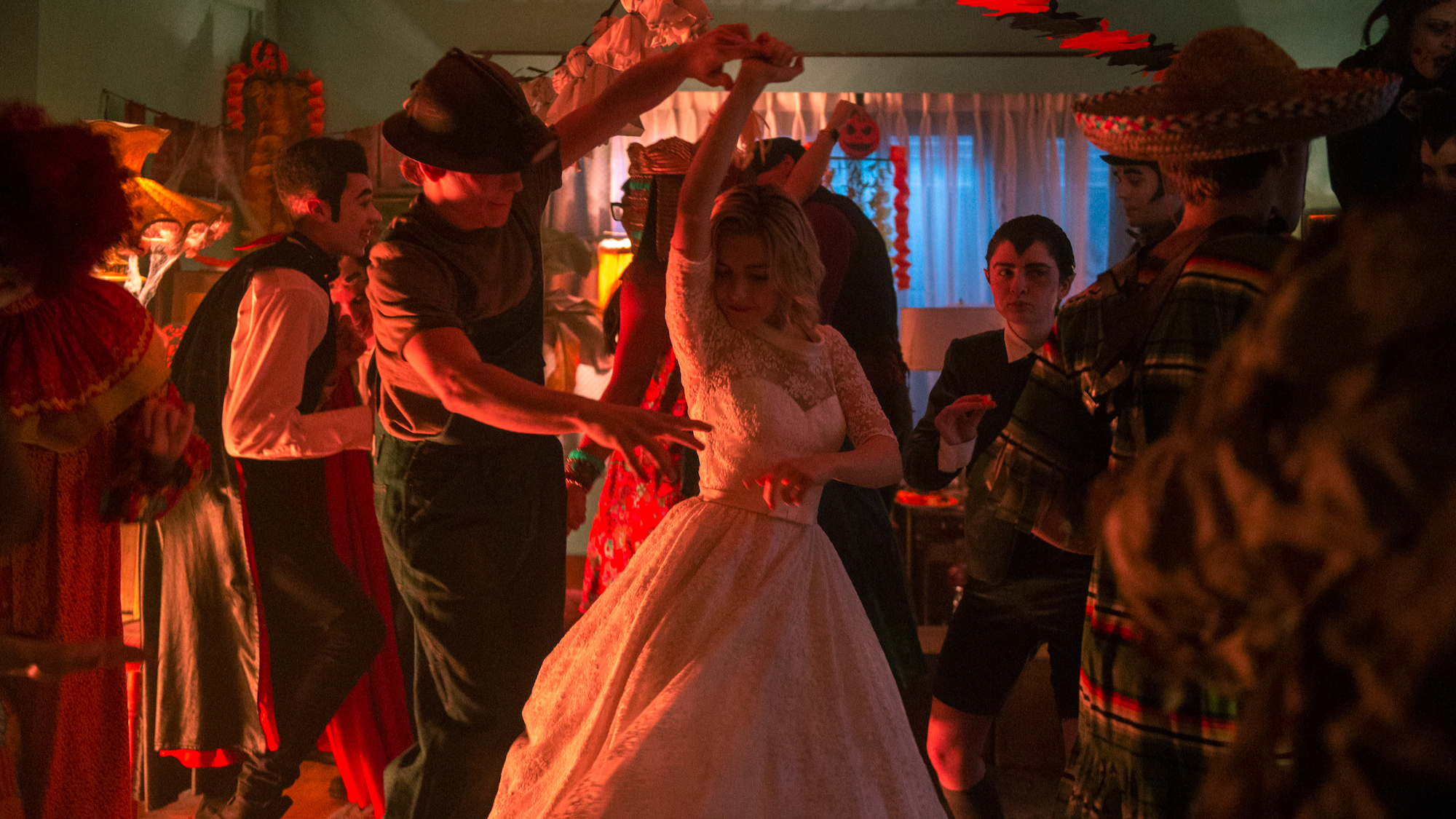 Teenagers in Halloween costumes dance in a living room.