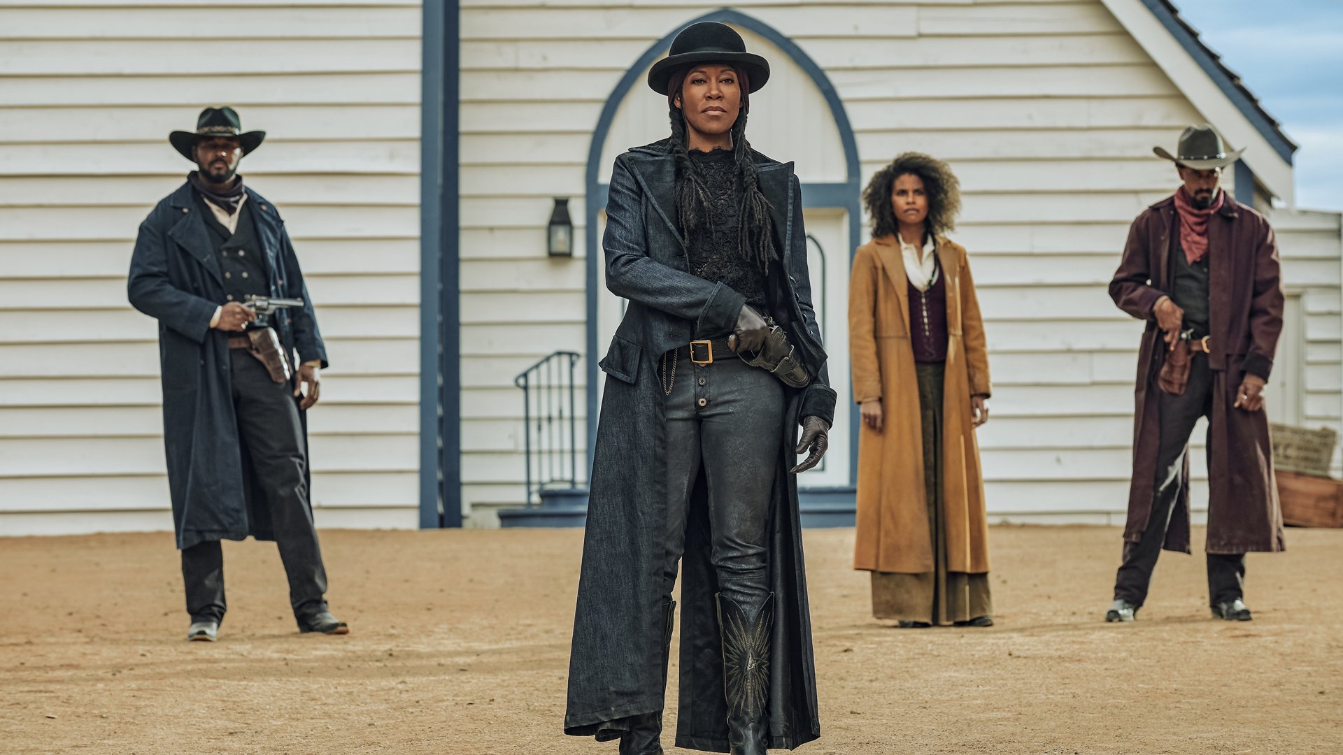 Four people in Wild West outlaw costumes stand in front of a church.