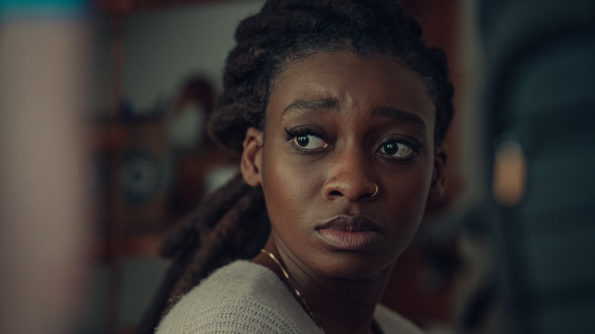 A woman looks over her shoulder, looking worried.