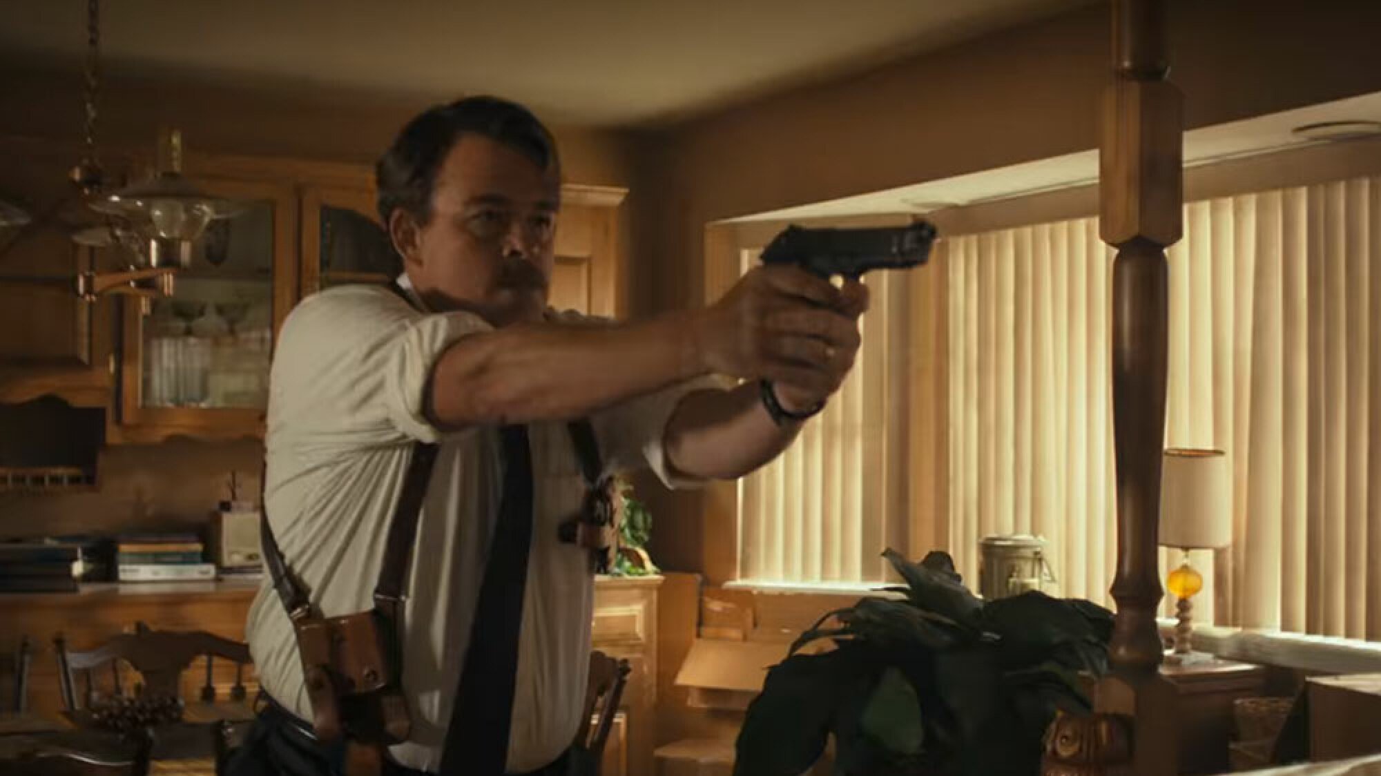 A man in a shirt and tie points a gun