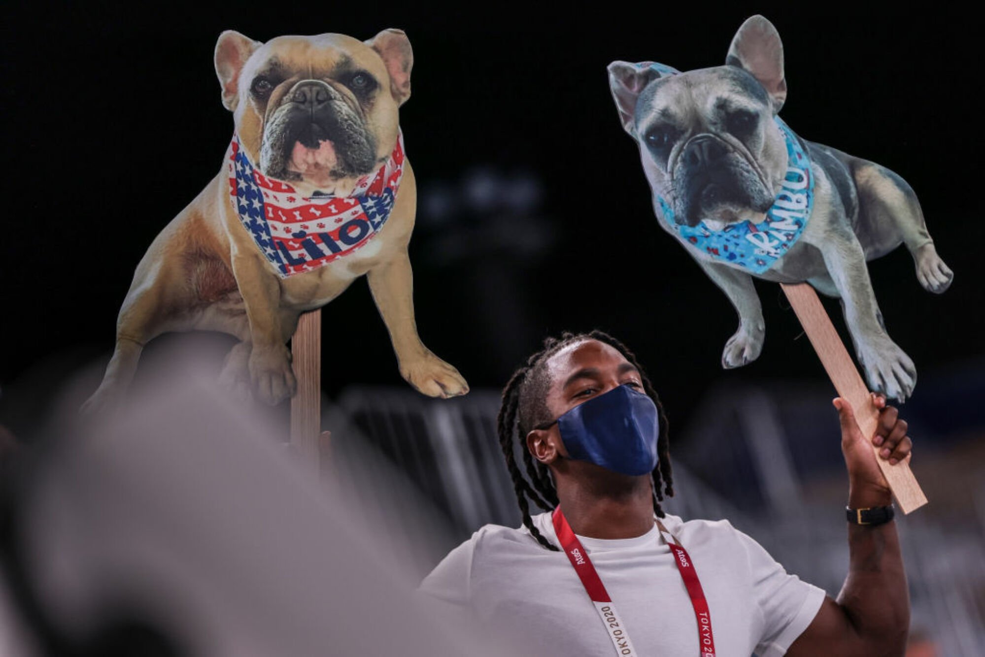 Image of a fan holding up photo cutouts of Simone Biles' dogs