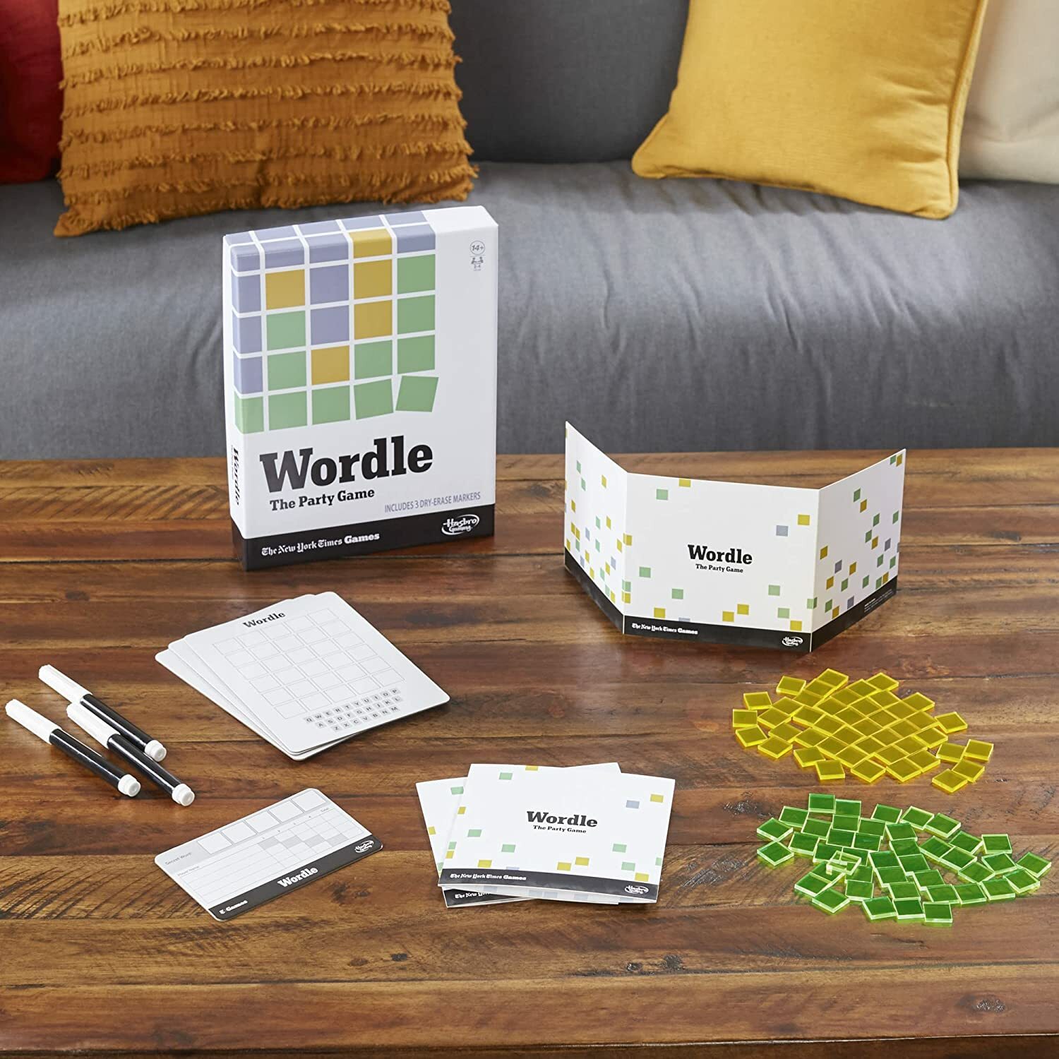 "wordle: the party game" laid out on a wooden table in front of a couch with colorful throw pillows