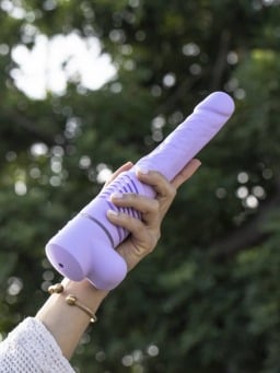 person holding lilac self-thrusting dildo
