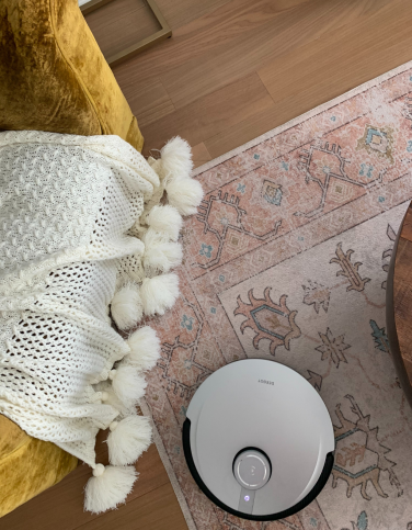 Deebot X1 Omni robot vacuum cleaning between yellow chair and coffee table