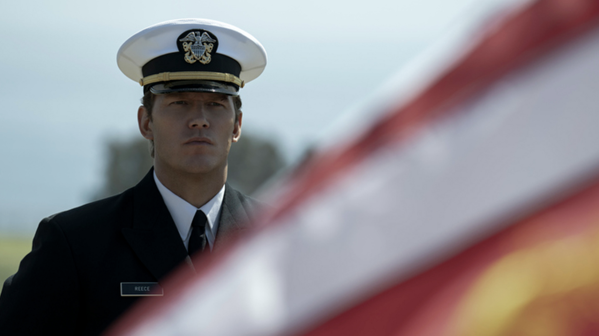 A man stands to attention in military uniform looking serious.