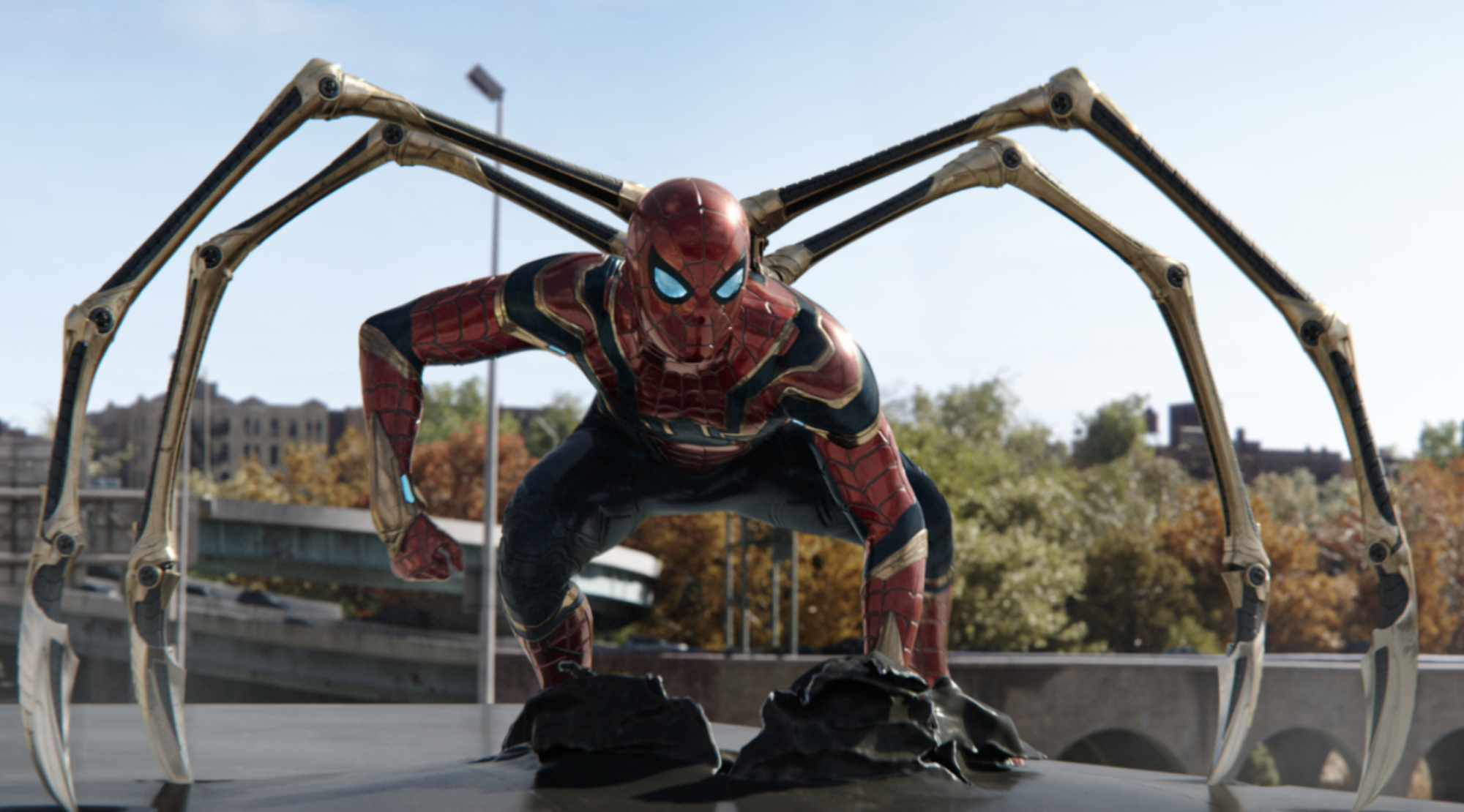 A man in a red superhero costume crouches with metal limbs protruding from his back.
