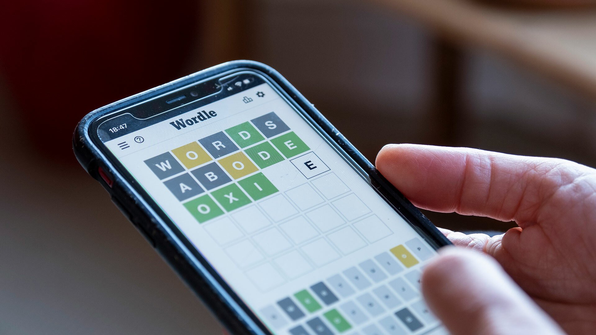 A close up of a person playing Wordle on a smartphone.