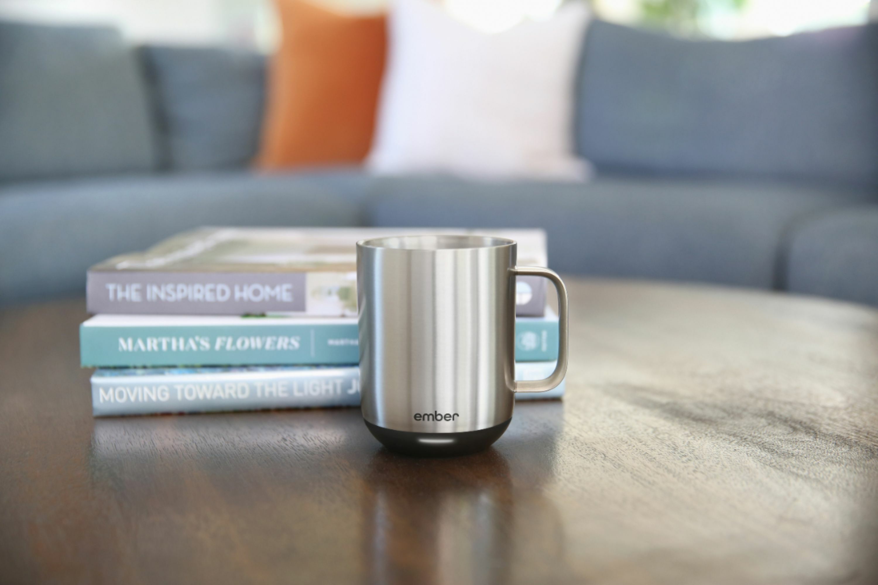 stainless steel ember mug on a coffee table in front of some books
