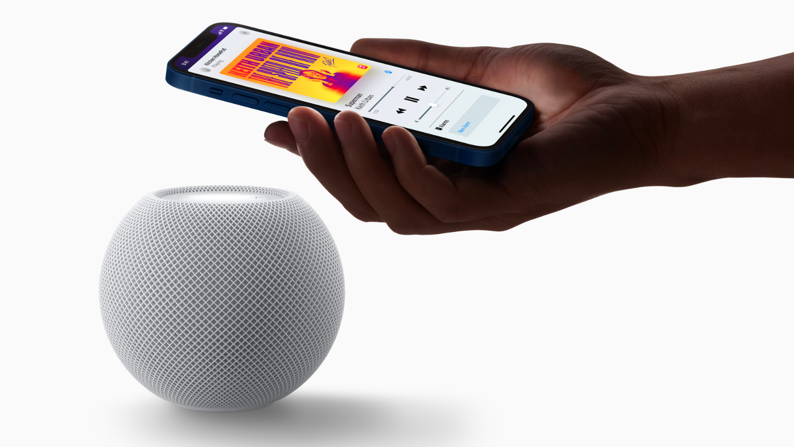 a close-up of a person holding an iphone over an apple homepod mini