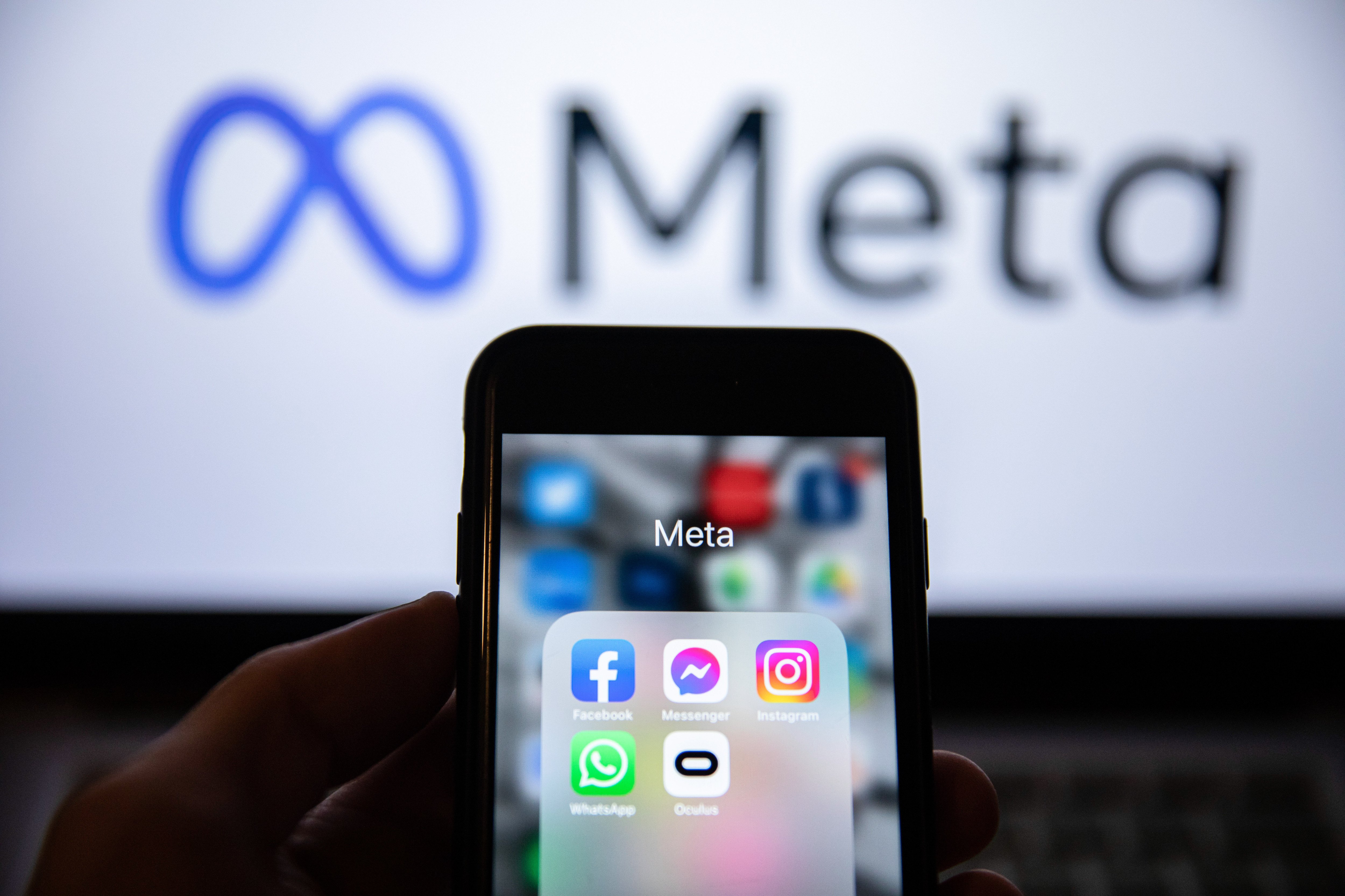 A smartphone showing apps by Meta Platforms with the Meta logo in the background