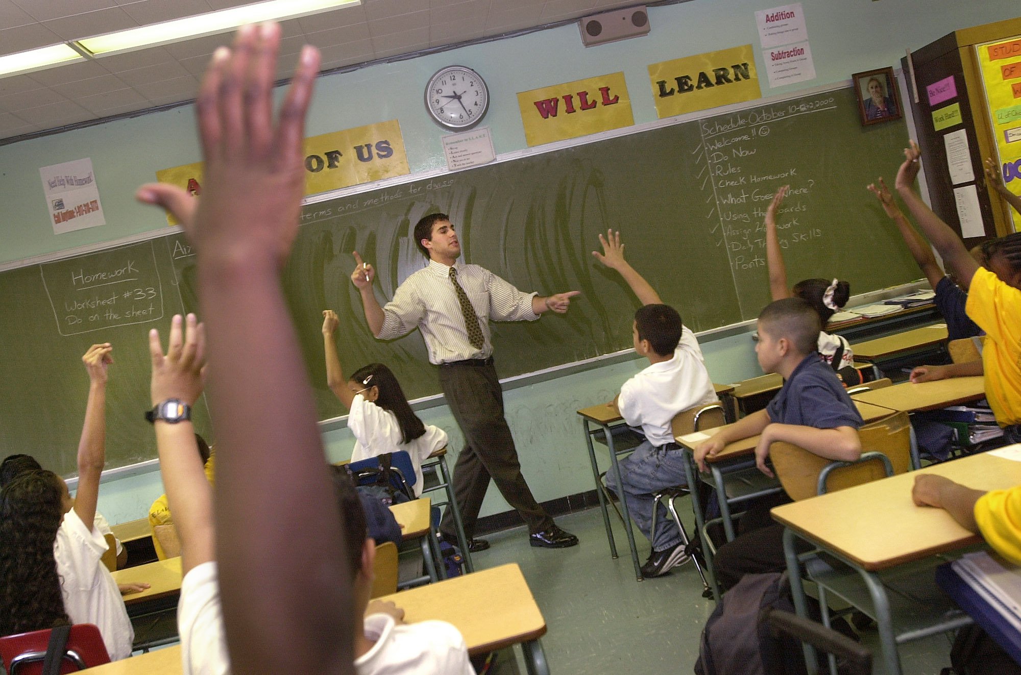 kids in a classroom raising their hands