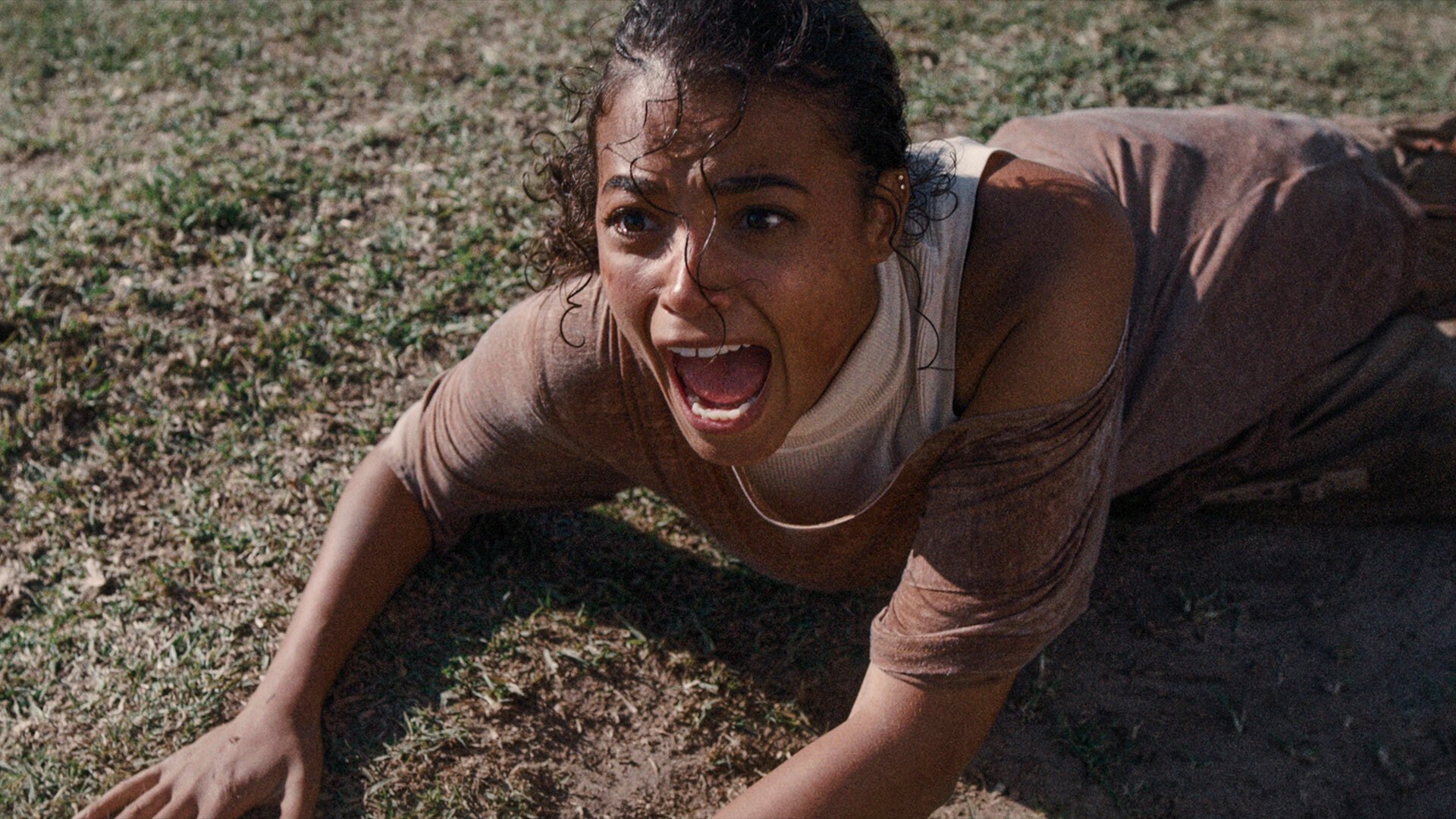 A woman lies on the ground screaming.