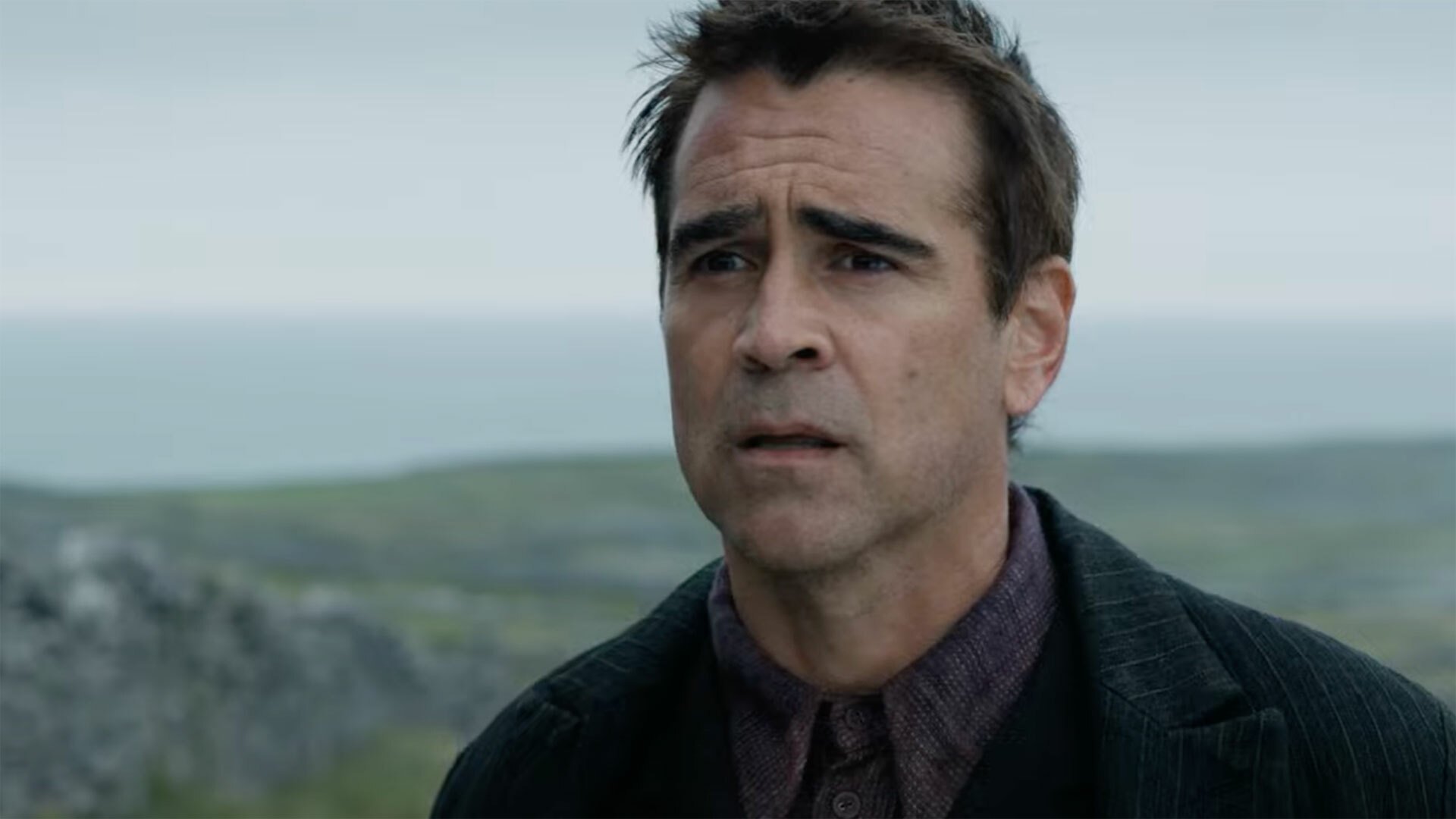 A man stands on the coast looking confused.