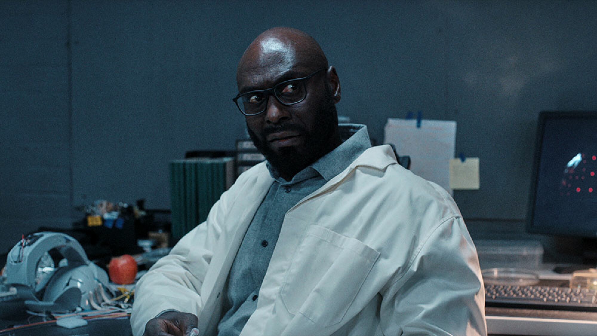 A man with glasses and a beard sits in a laboratory.