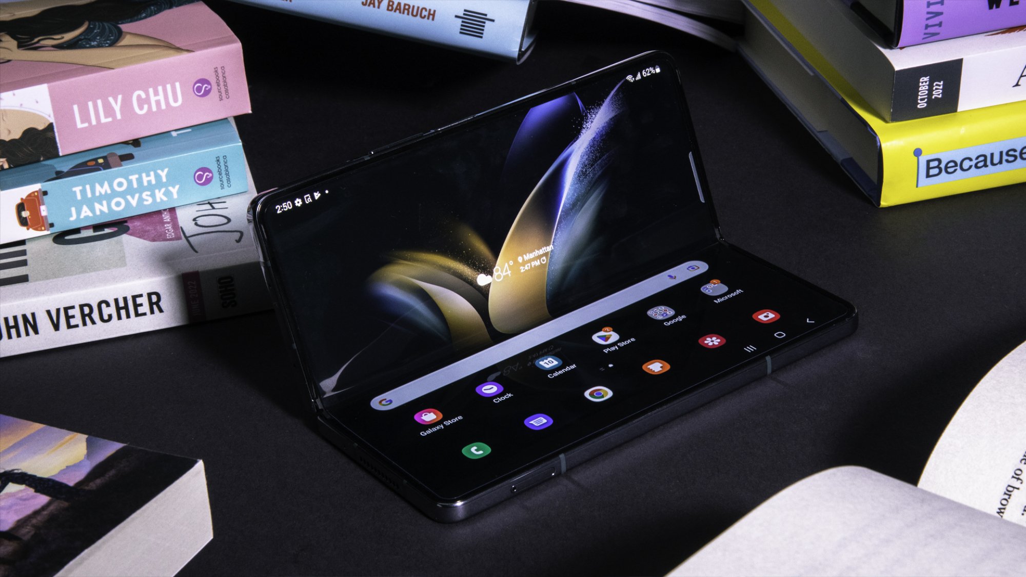 Samsung Galaxy Z Fold 4 half open with inner display visible and surrounded by physical books