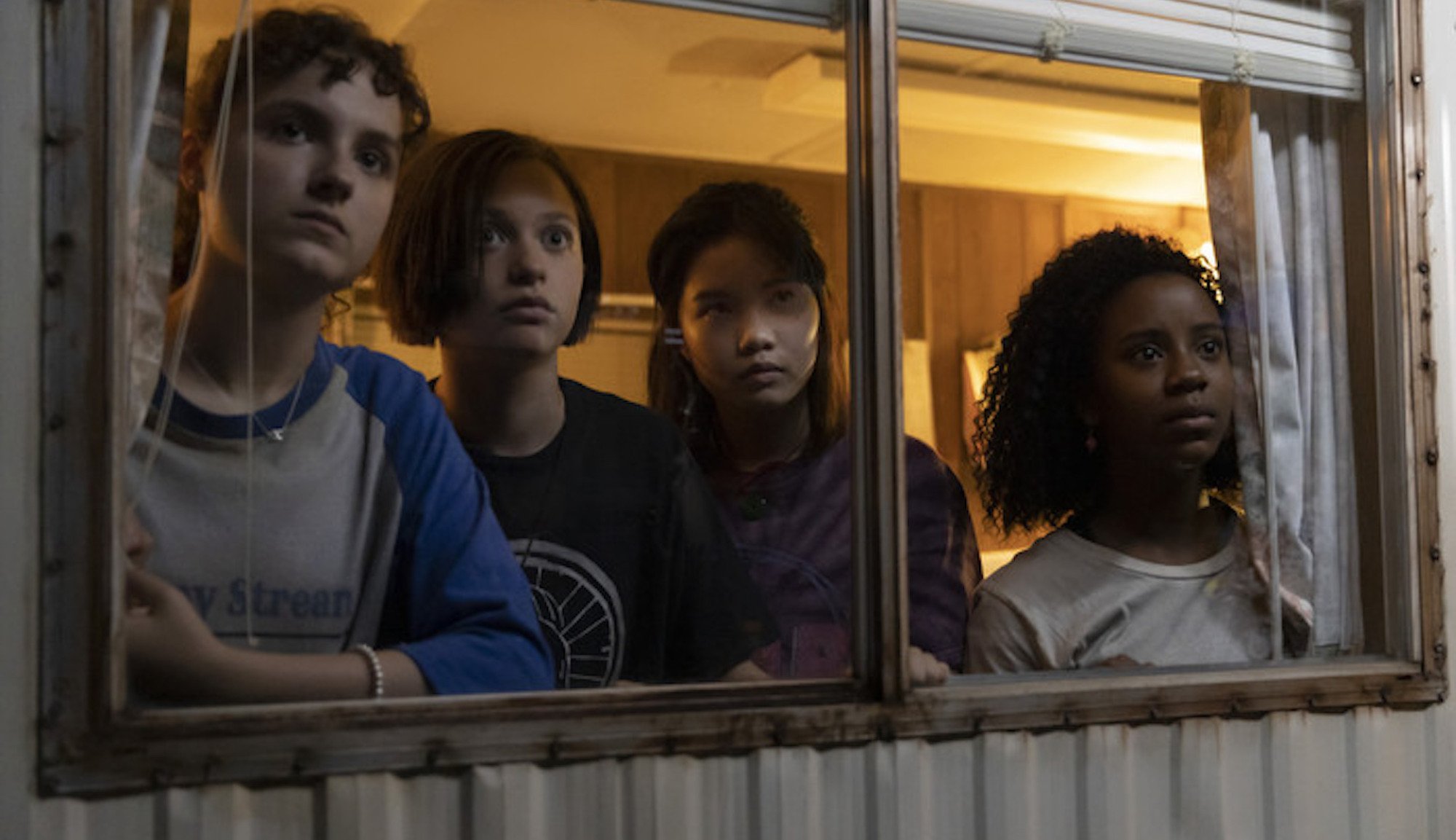 Four teens look out a window.