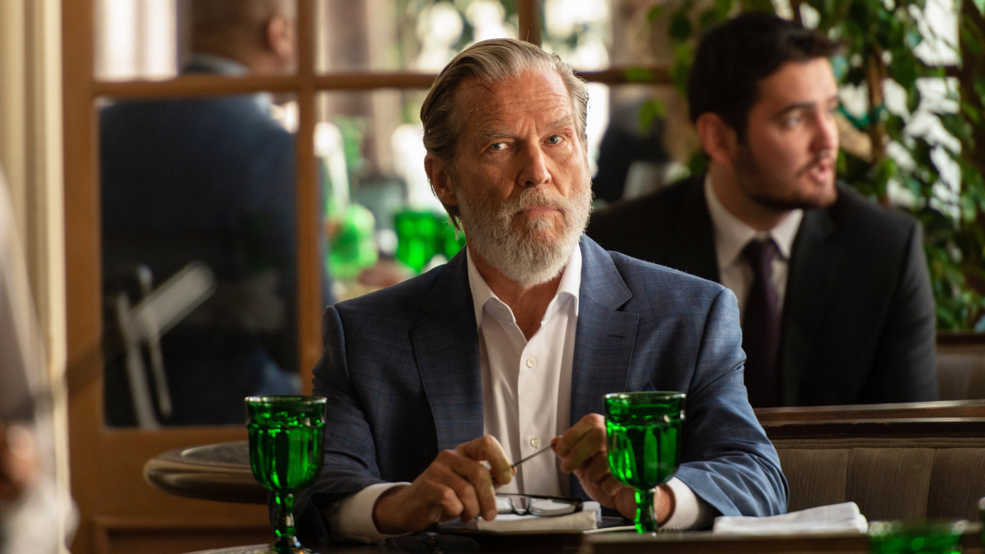 A man in a suit sits in a restaurant.