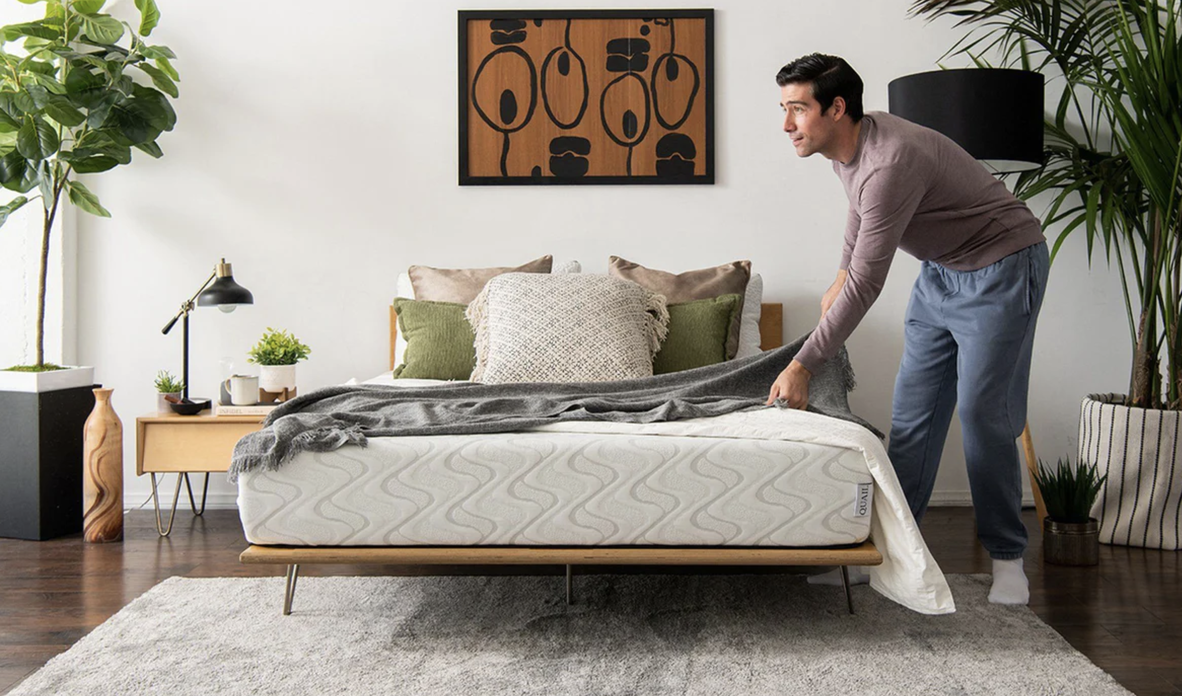 Man making a bed in a bright bedroom
