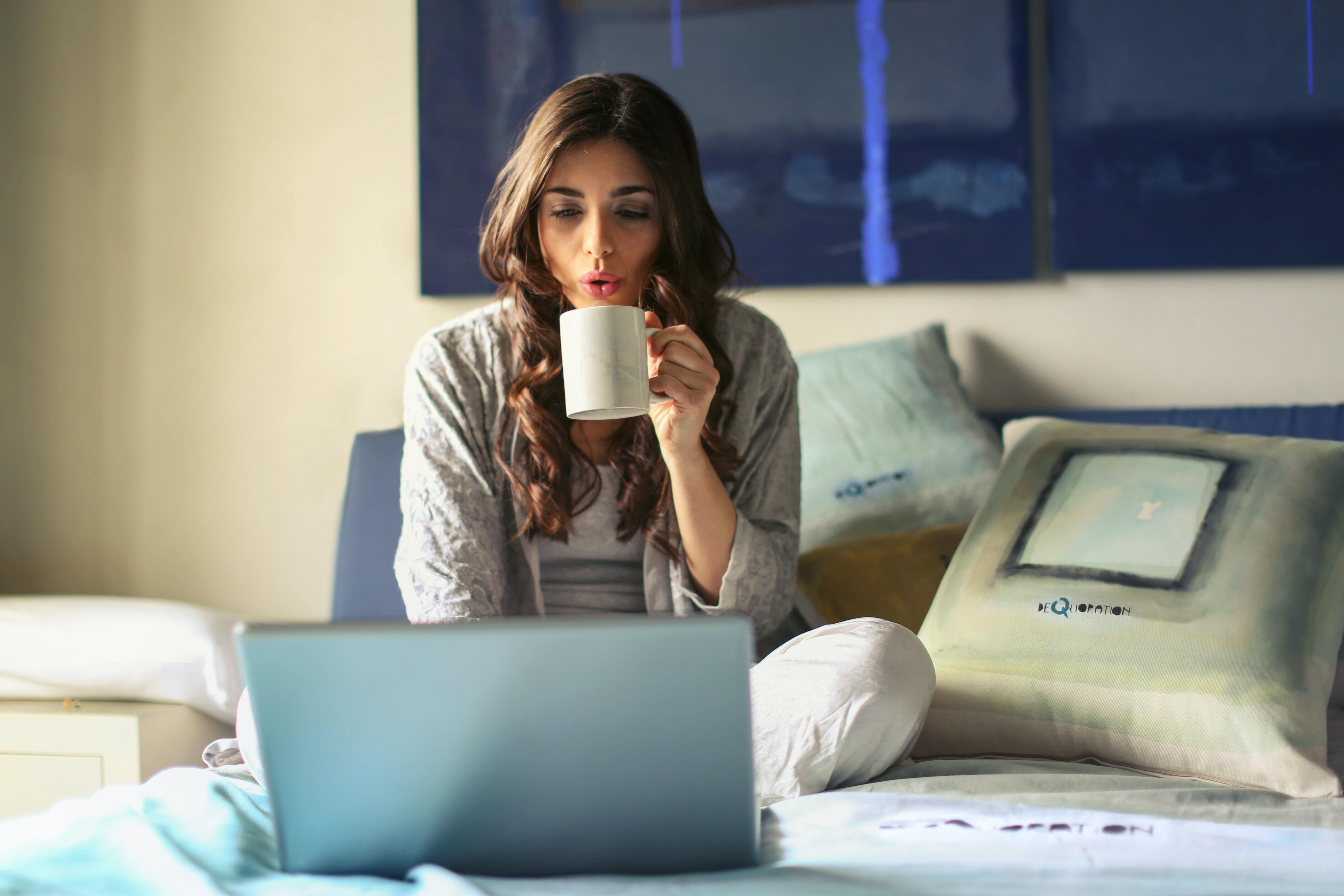 Girl with mug looking at laptop