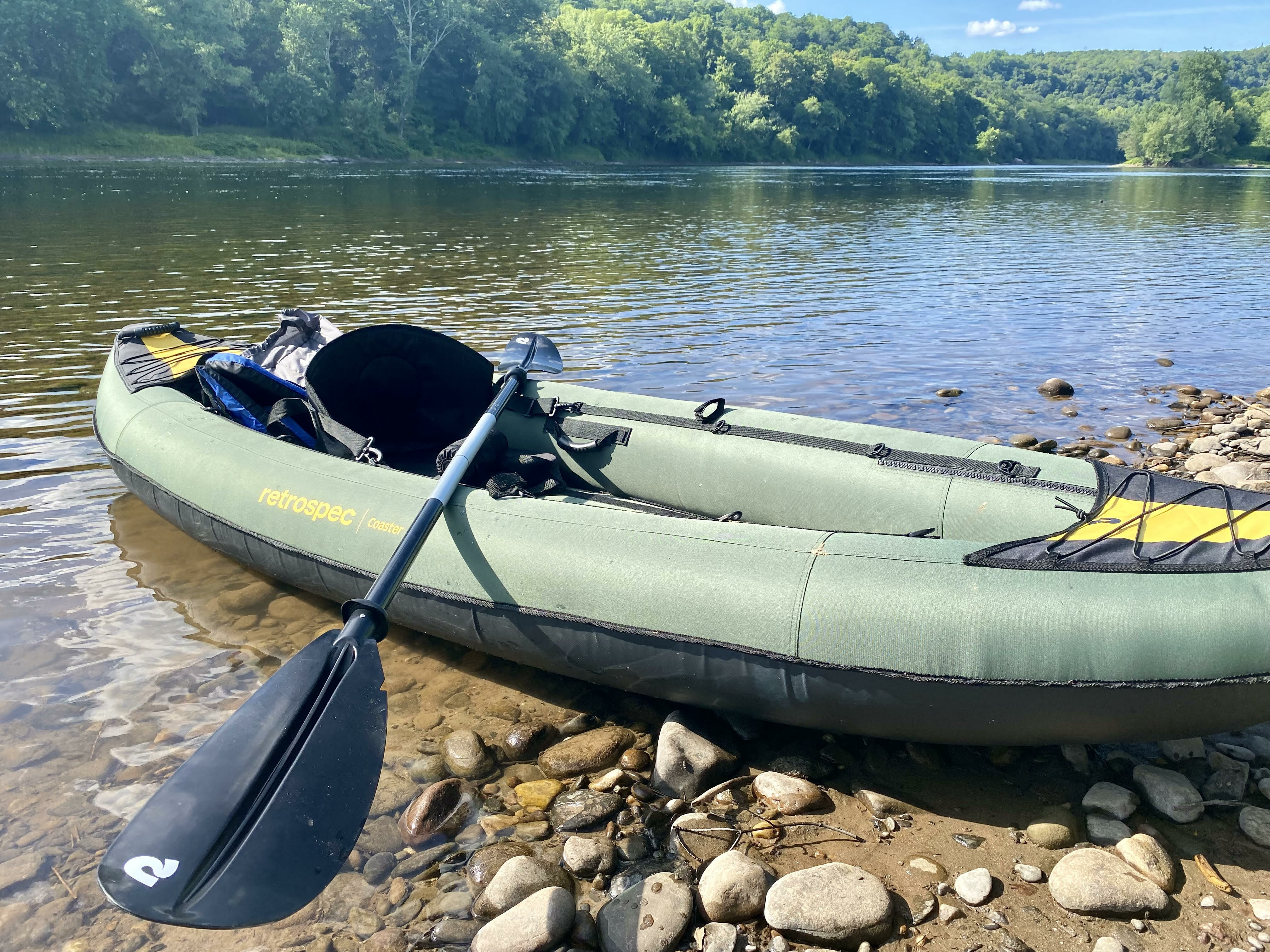 Green inflatable kayak on the bank of a river