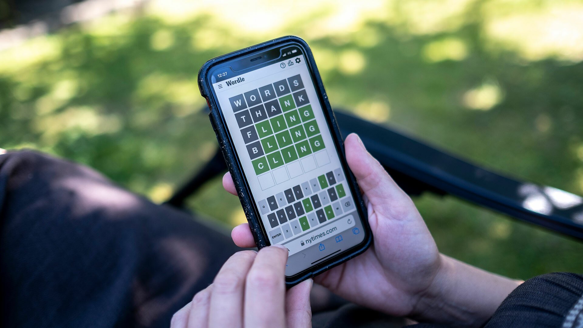 A person sits in their garden playing Wordle.