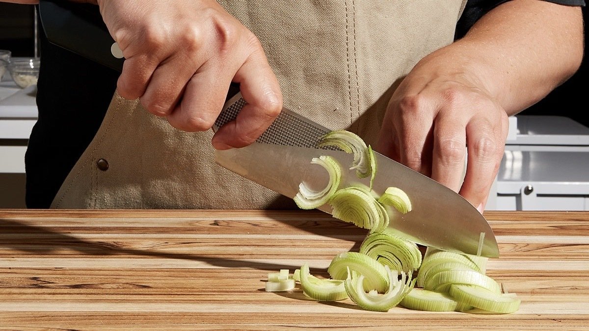 Person cooking with the Milk Street Santoku Knife.