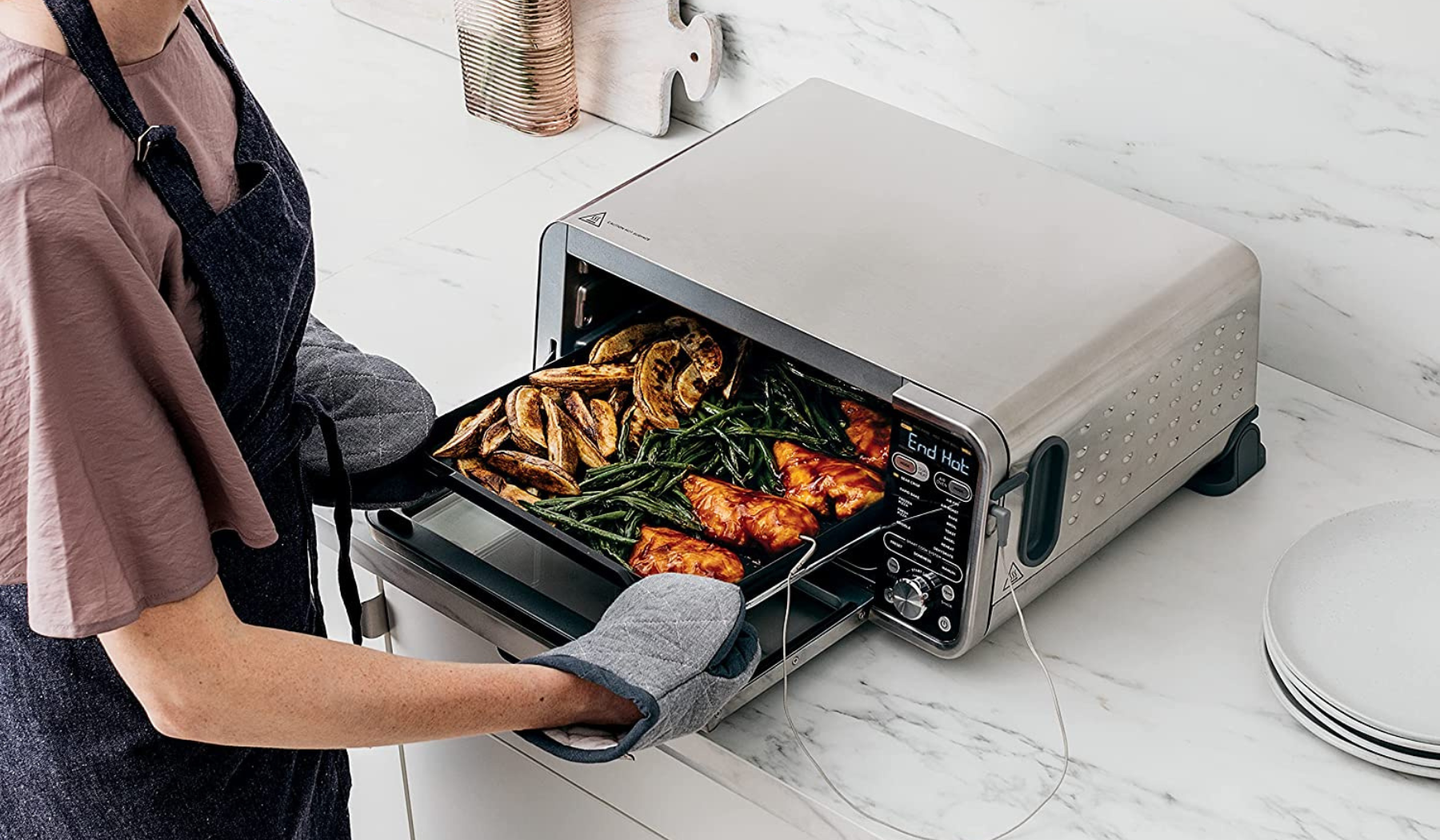 Person taking food out of Ninja Foodi oven on countertop