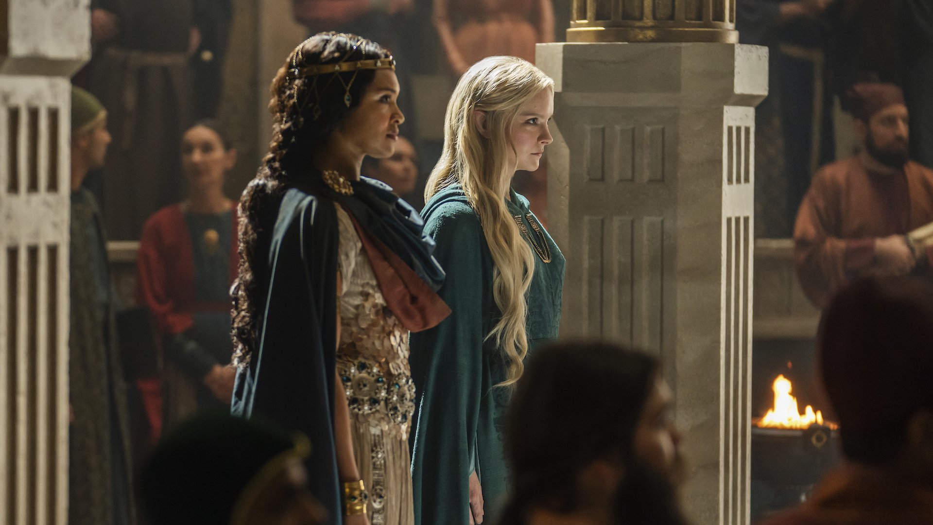 Two women in fantasy series costumes stand in a throne room.
