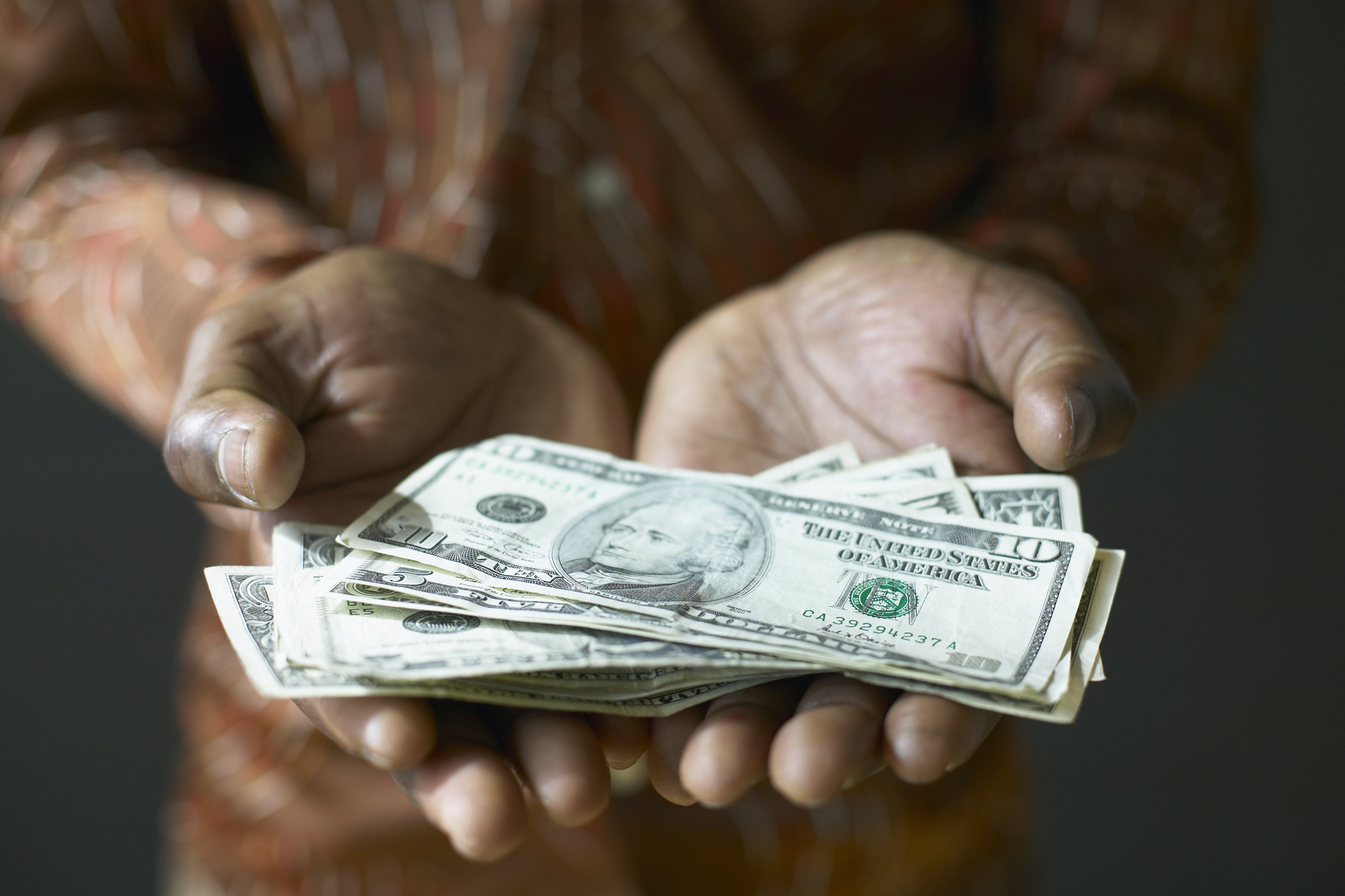 A pair of hands hold out a stack of money.