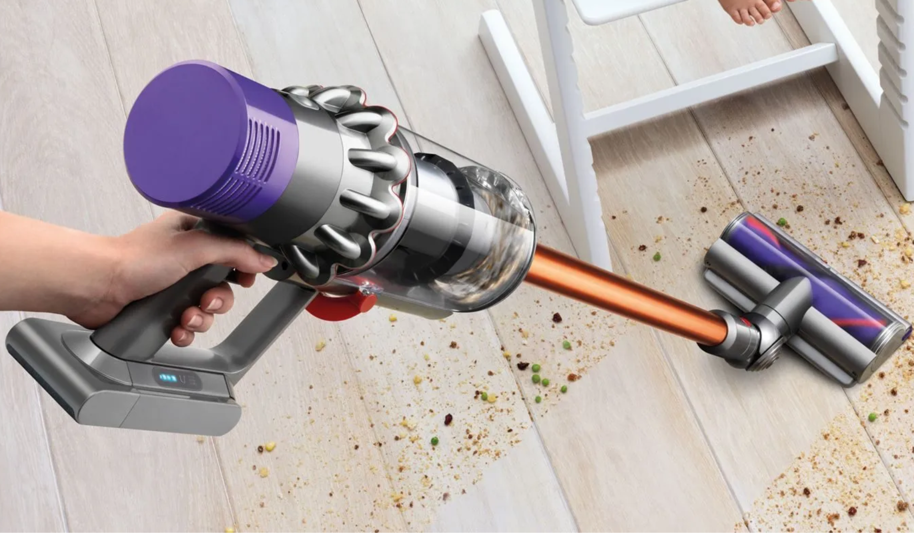 Hand holding Dyson cordless vacuum cleaning hardwood floor